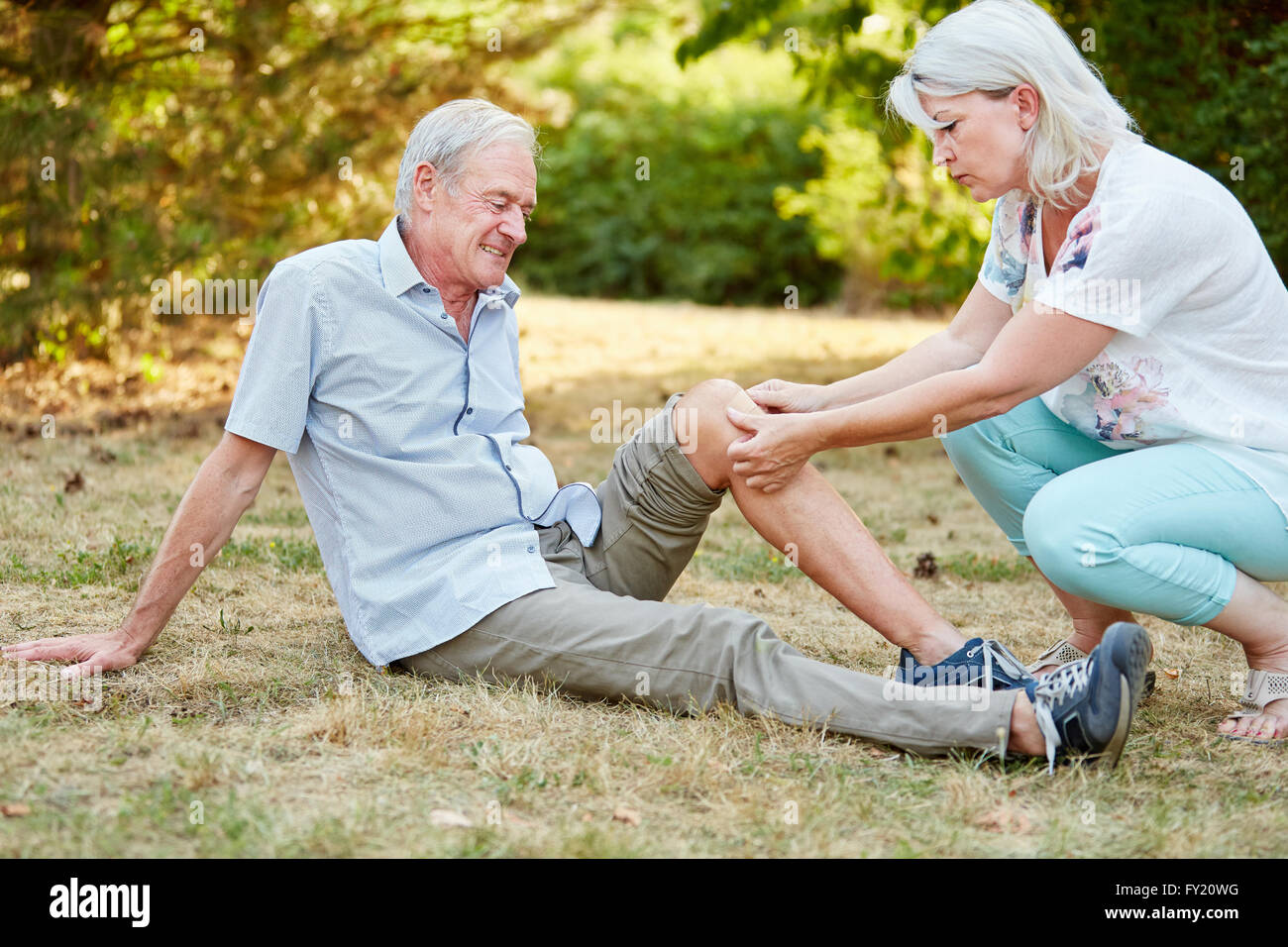 Woman practice first aid on the knee of an old man and puts a plaster on it Stock Photo
