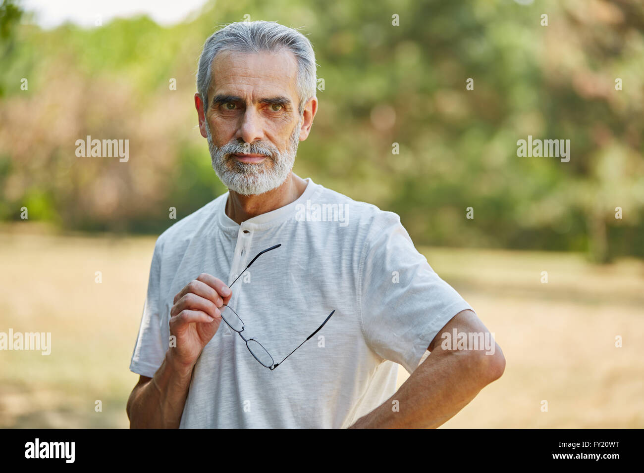 Senior retiree man looking pensive in summer in the nature Stock Photo