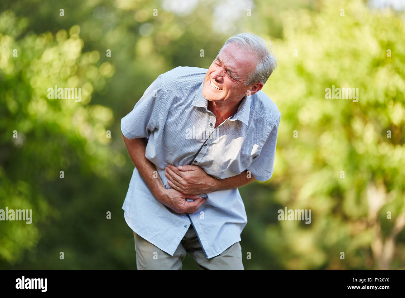 Old man with stomach ache toching his stomach in the nature Stock Photo