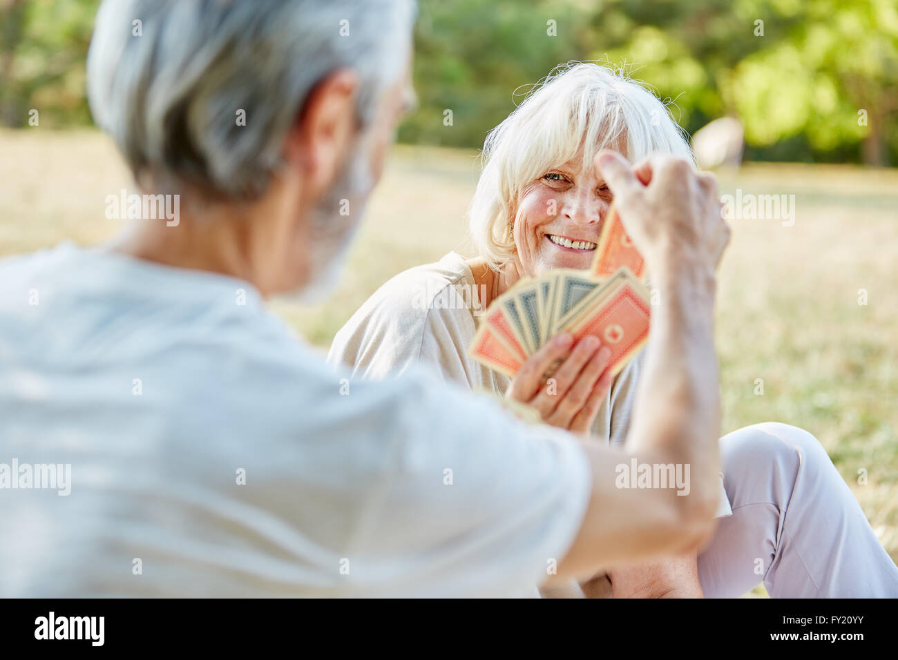 Seniors playing cards together in the garden in summer Stock Photo