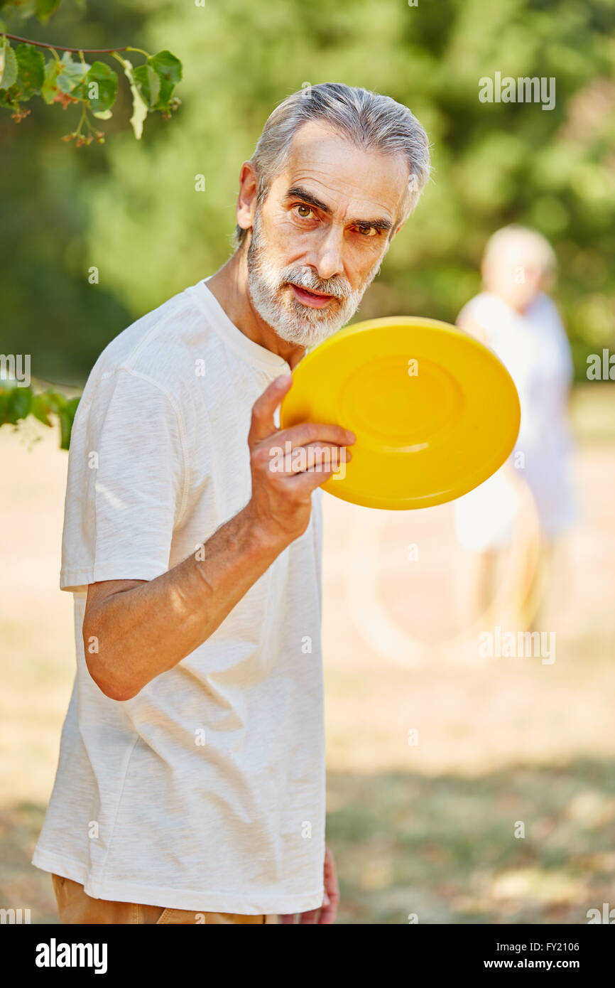 Old man with a frisbee disc in summer in the nature Stock Photo