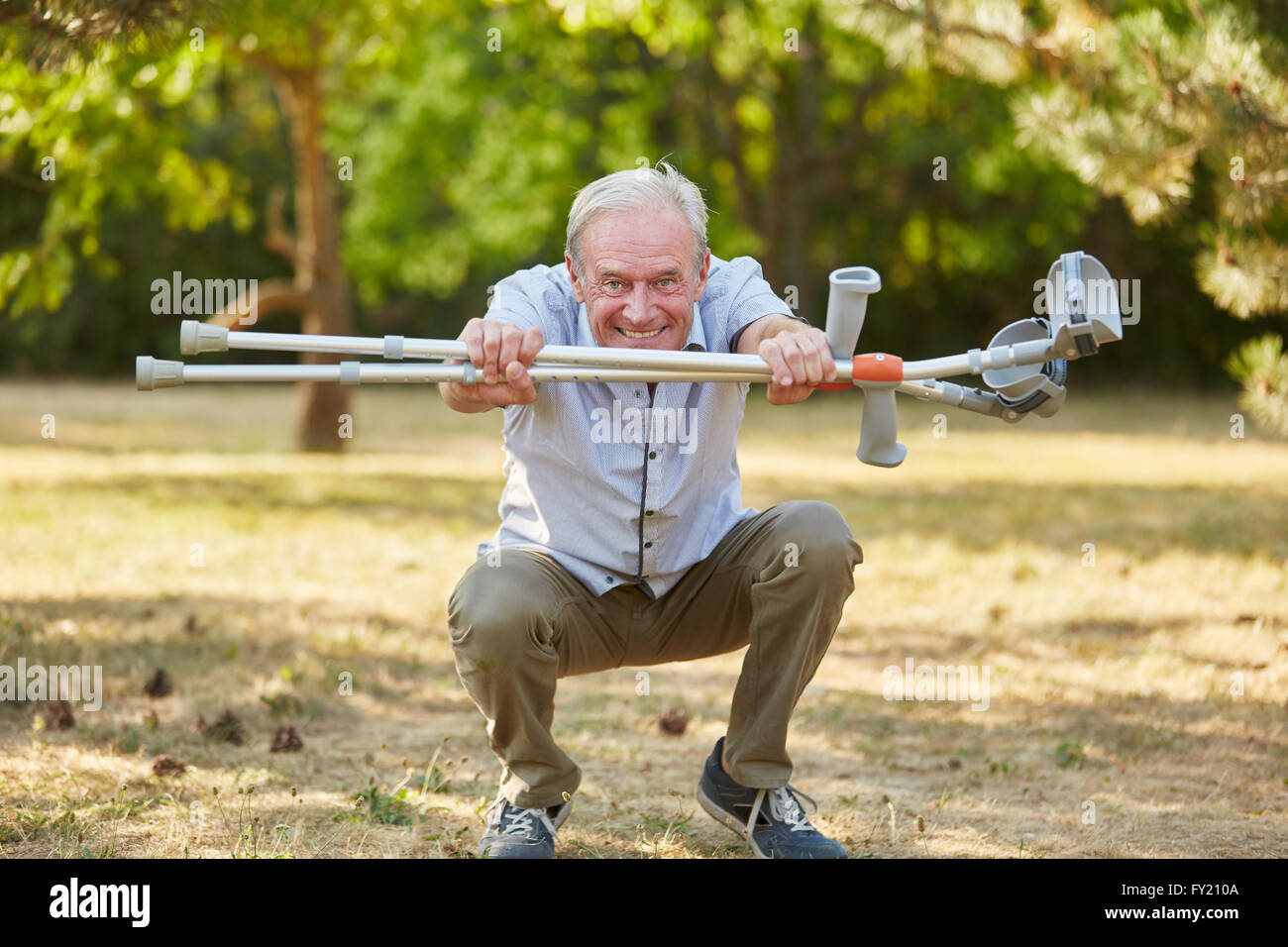 Old man with vitality and crutches in rehab having fun Stock Photo