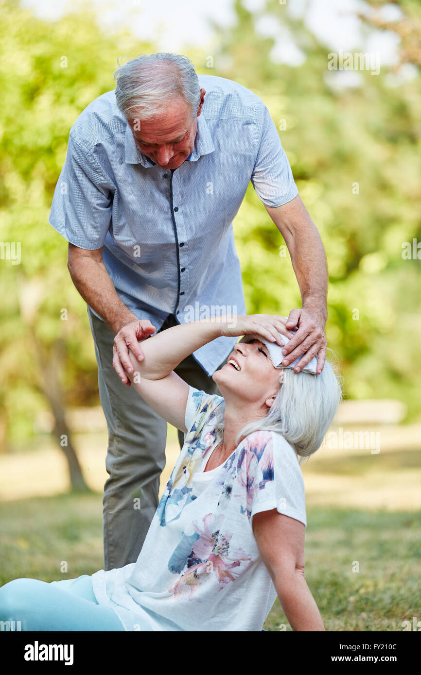Senior man holds wet cloth on a fainting woman's forhead Stock Photo