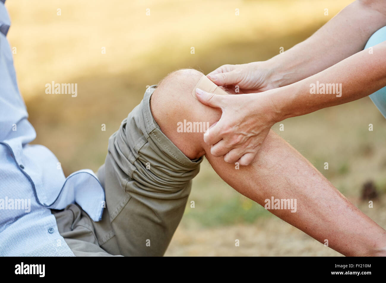 Woman puts a band aid on an injured knee and helps the man Stock Photo