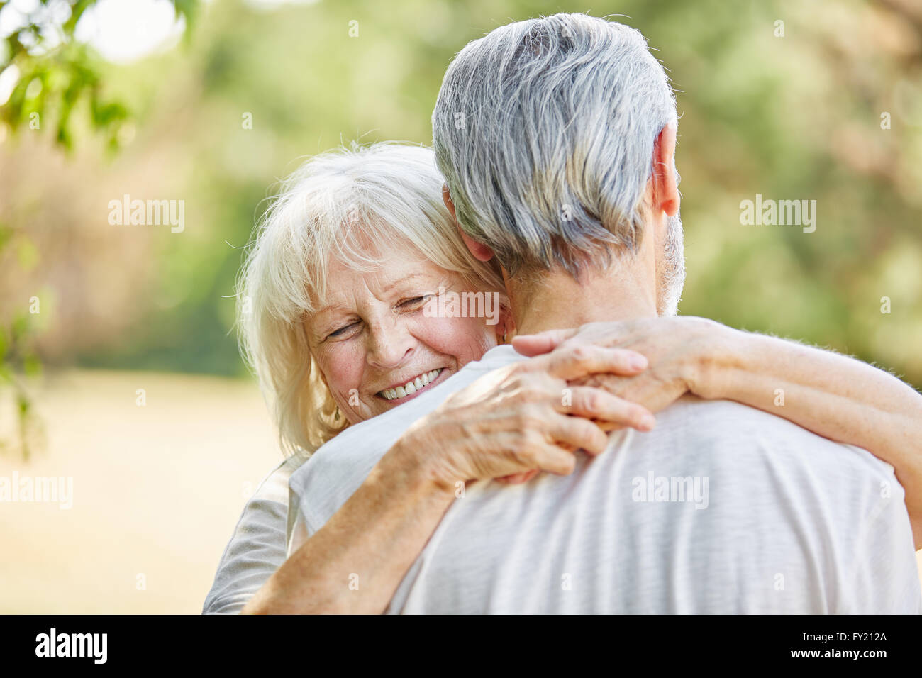 Happy old lady hugging a man in the nature in summer Stock Photo