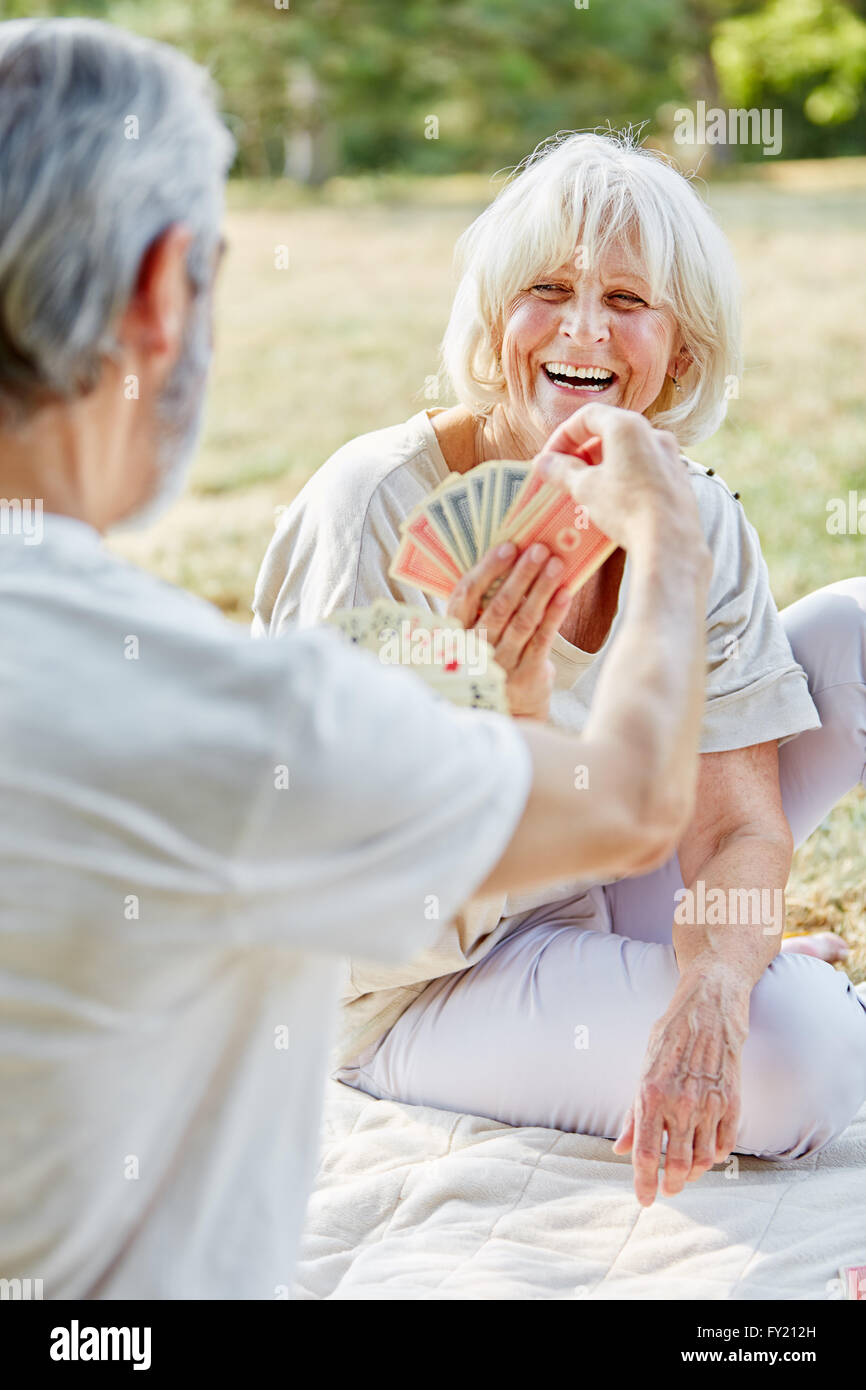 Two pensioners playing cards in the garden having fun Stock Photo