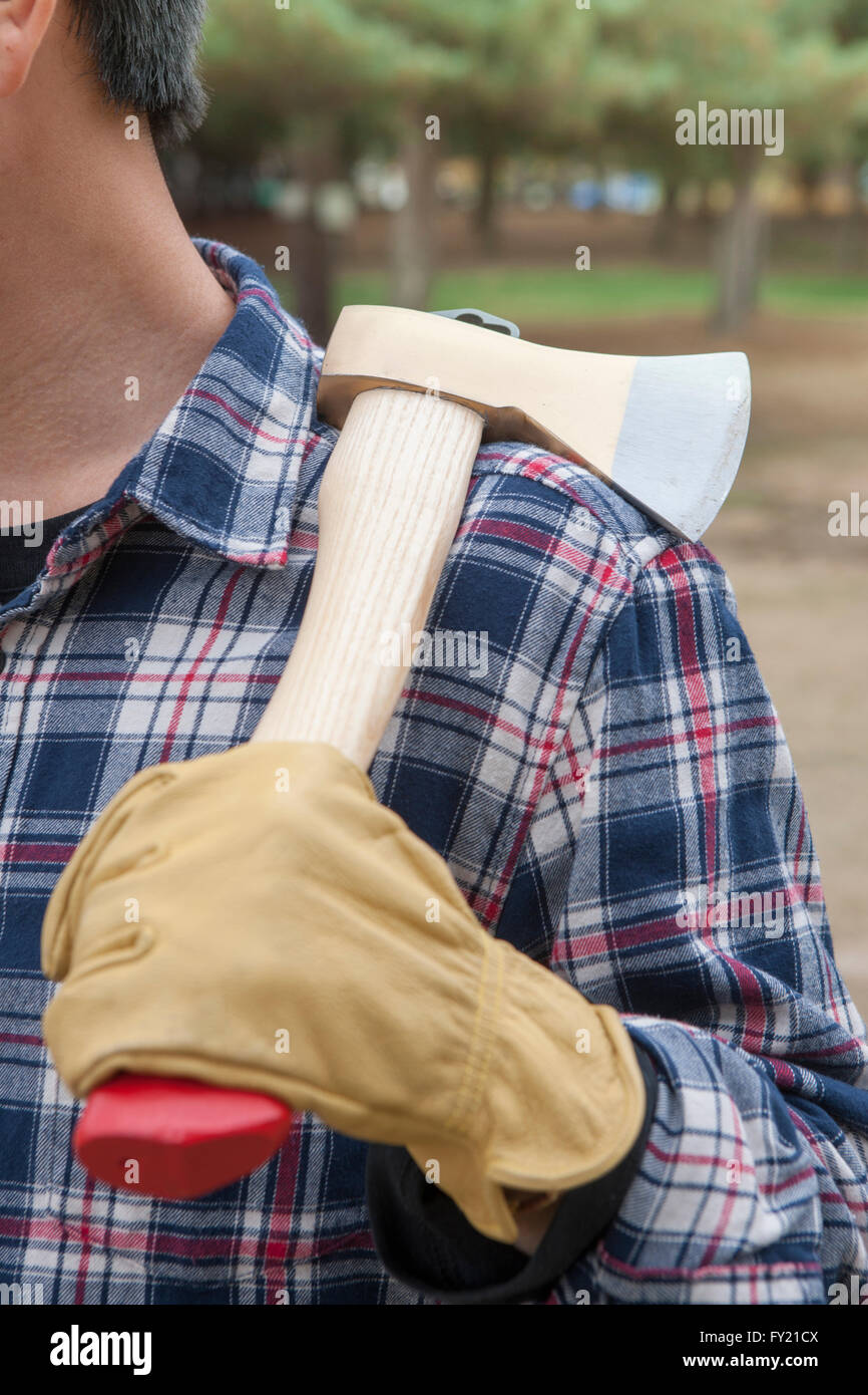 Man in gloves holding an ax over his shoulder Stock Photo