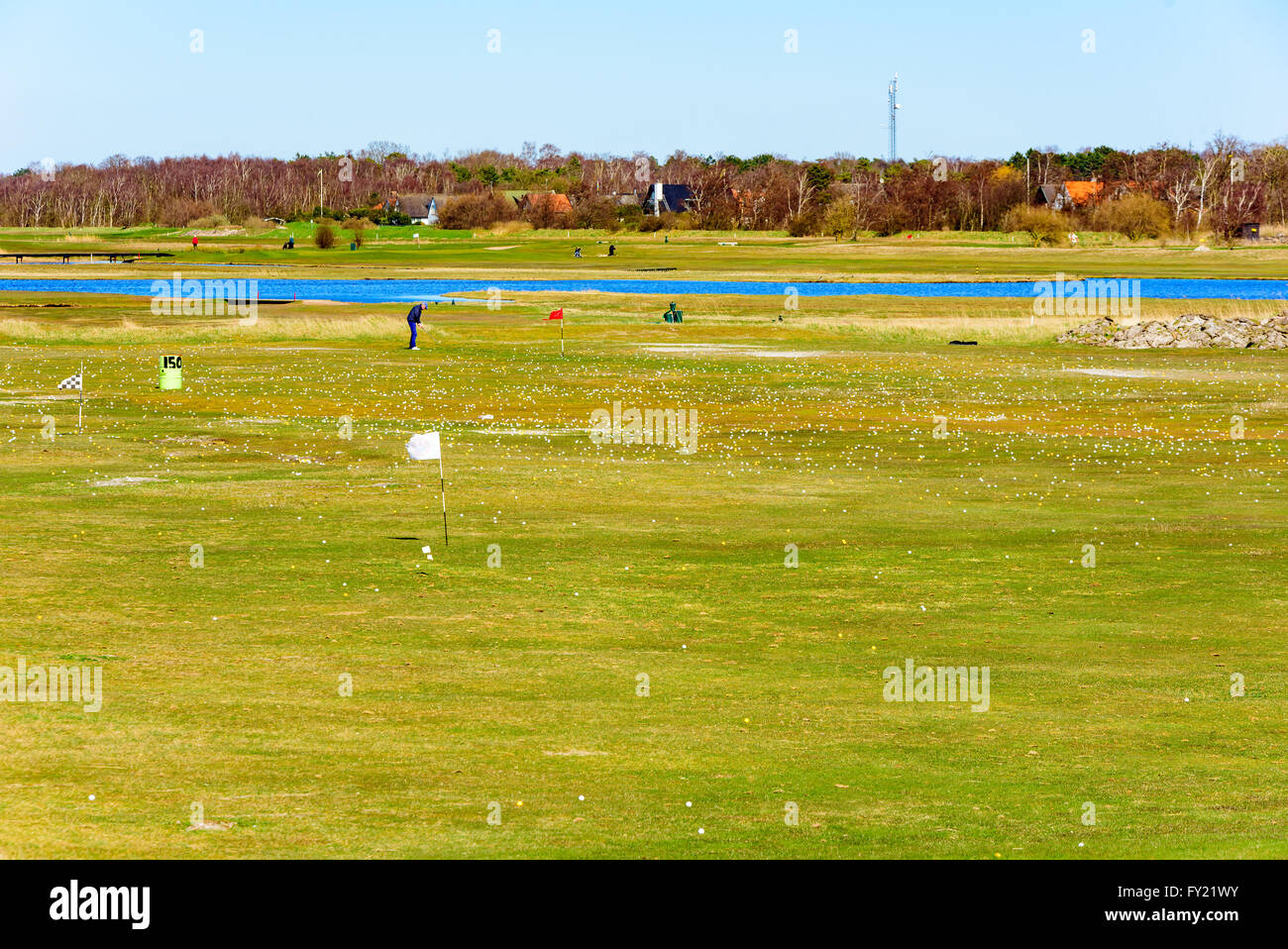 Falsterbo, Sweden - April 11, 2016: Driving range full of golf balls. A golfer is practicing his swing in the distance by the wa Stock Photo
