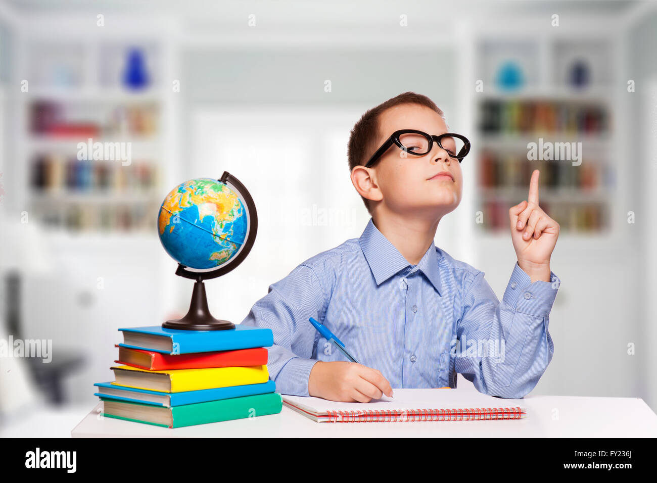 Cute schoolboy is writting isolated on a white background Stock Photo