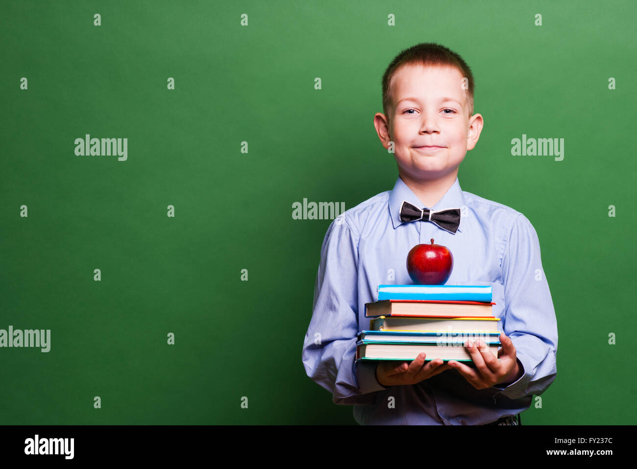 Happy little boy with books isolated on green background Stock Photo