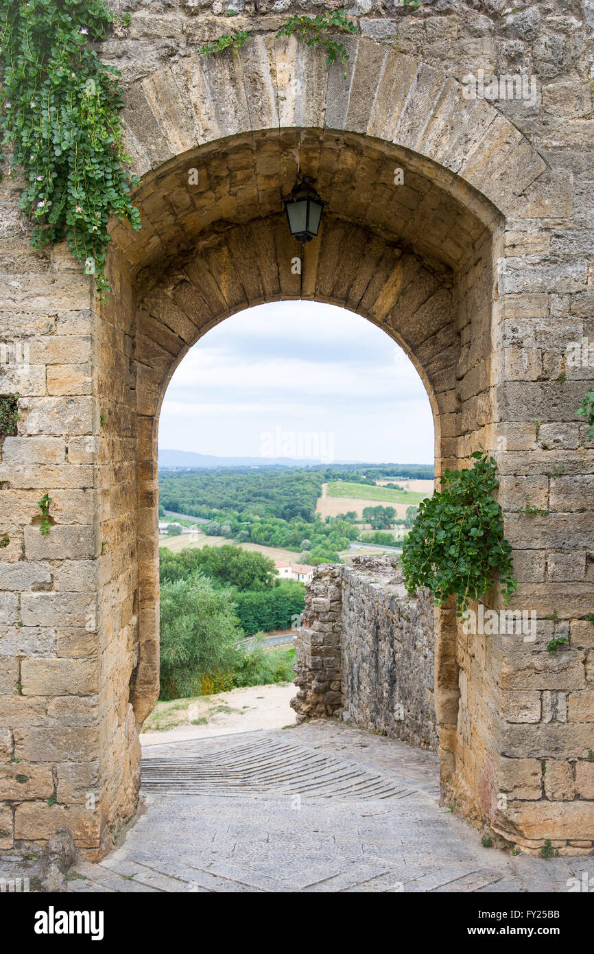 Arched doorway in a medieval stone wall in the Tuscan village of Monteriggioni, Italy.  Travel, architecture, European heritage. Stock Photo