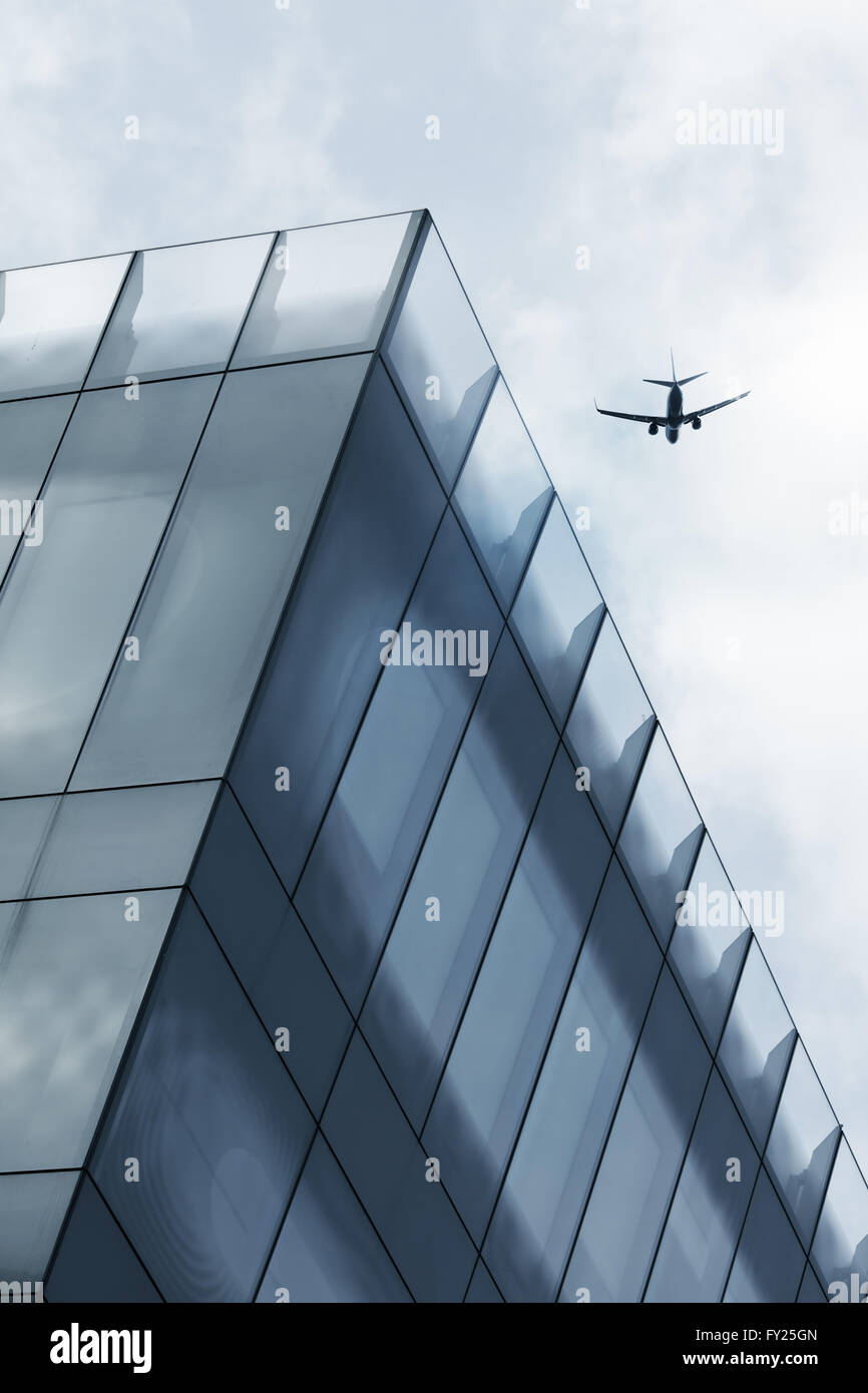 Aircraft flying over office tower Stock Photo