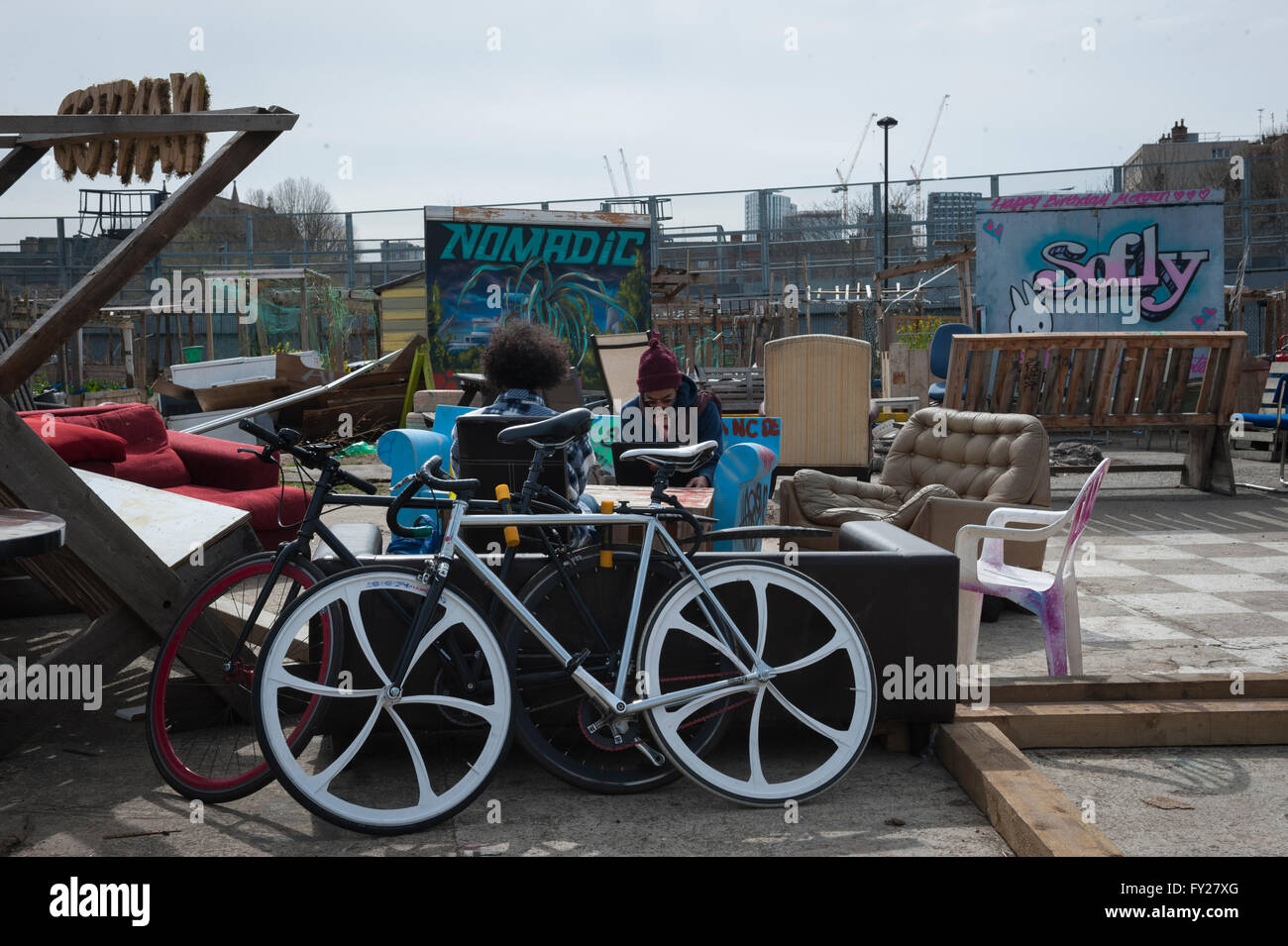 Two young men working on laptop in the Nomadic Community Gardens in Tower Hamlets, a bicycle Stock Photo