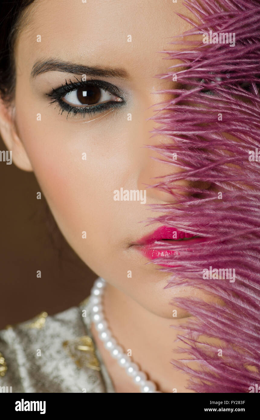 Beautiful Asian woman hiding face with a feather Stock Photo