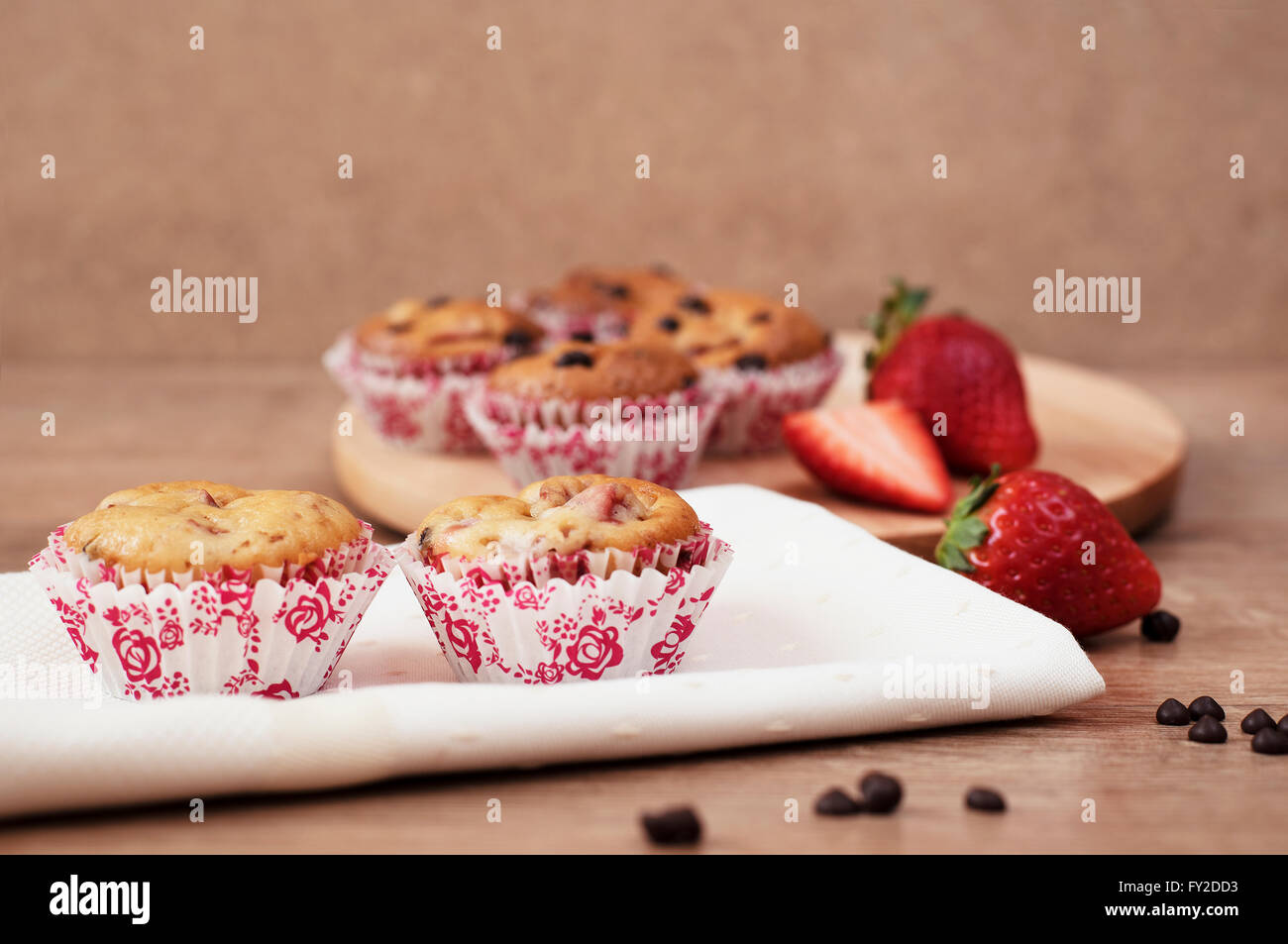 Strawberries and chocolate chip muffins on wooden background Stock Photo