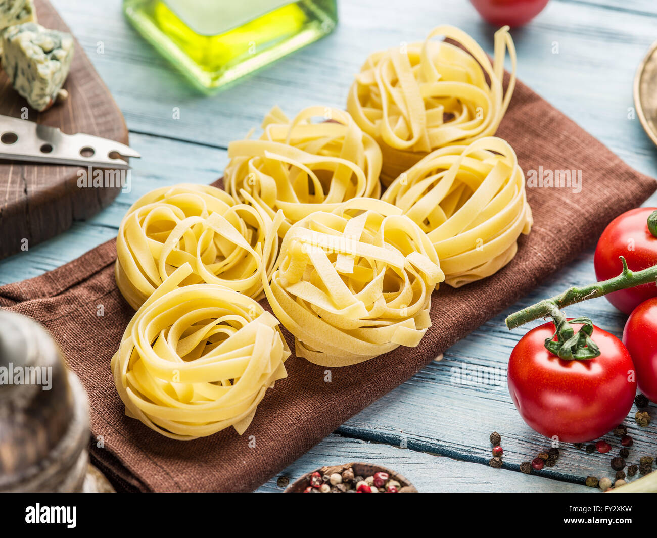 Pasta ingredients. Cherry-tomatoes, spaghetti pasta and spices on the wooden table. Stock Photo