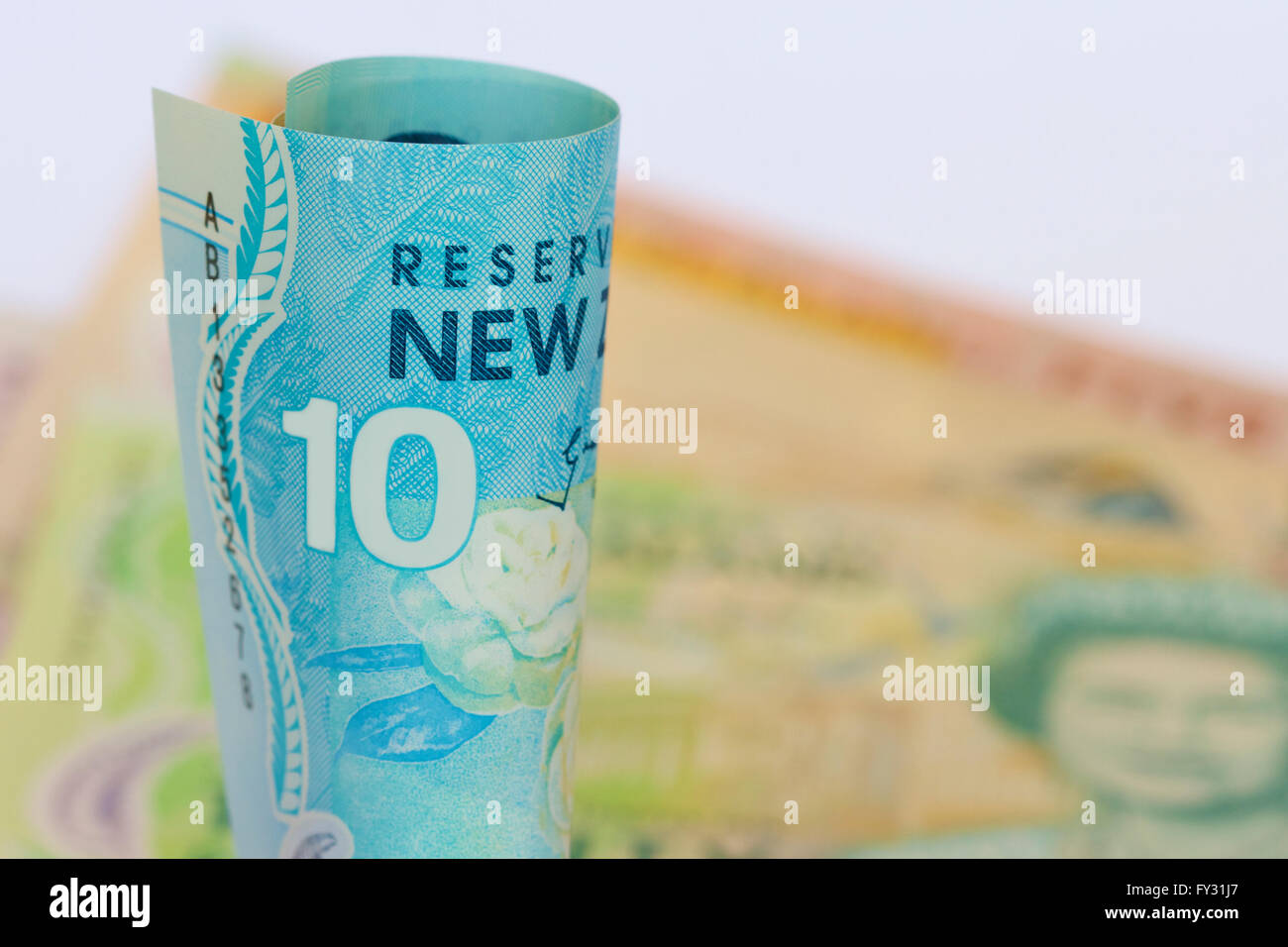 NZ dollars rolled with a background of notes. Stock Photo