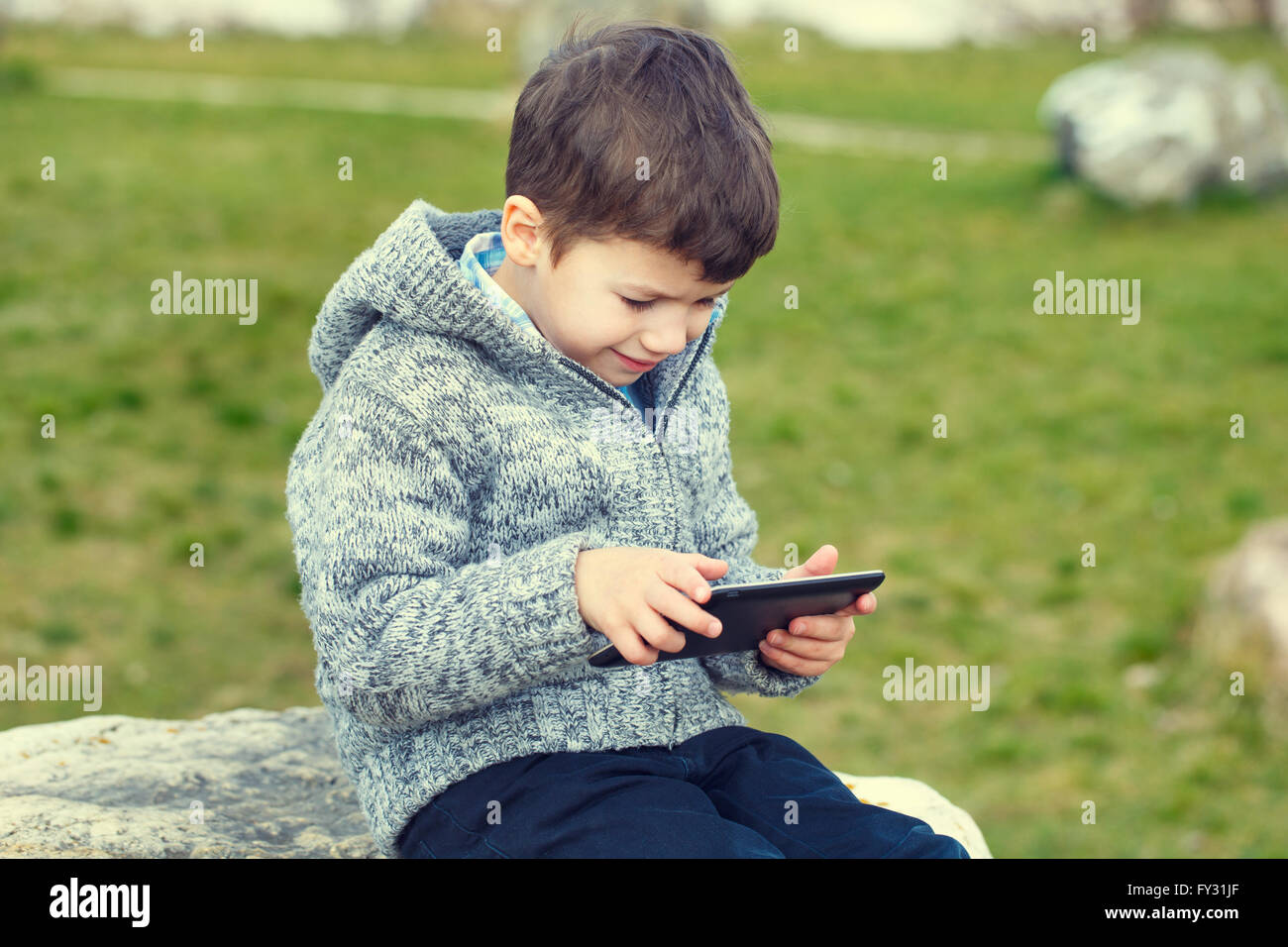 Little boy using tablet outdoor at spring or autumn Stock Photo - Alamy