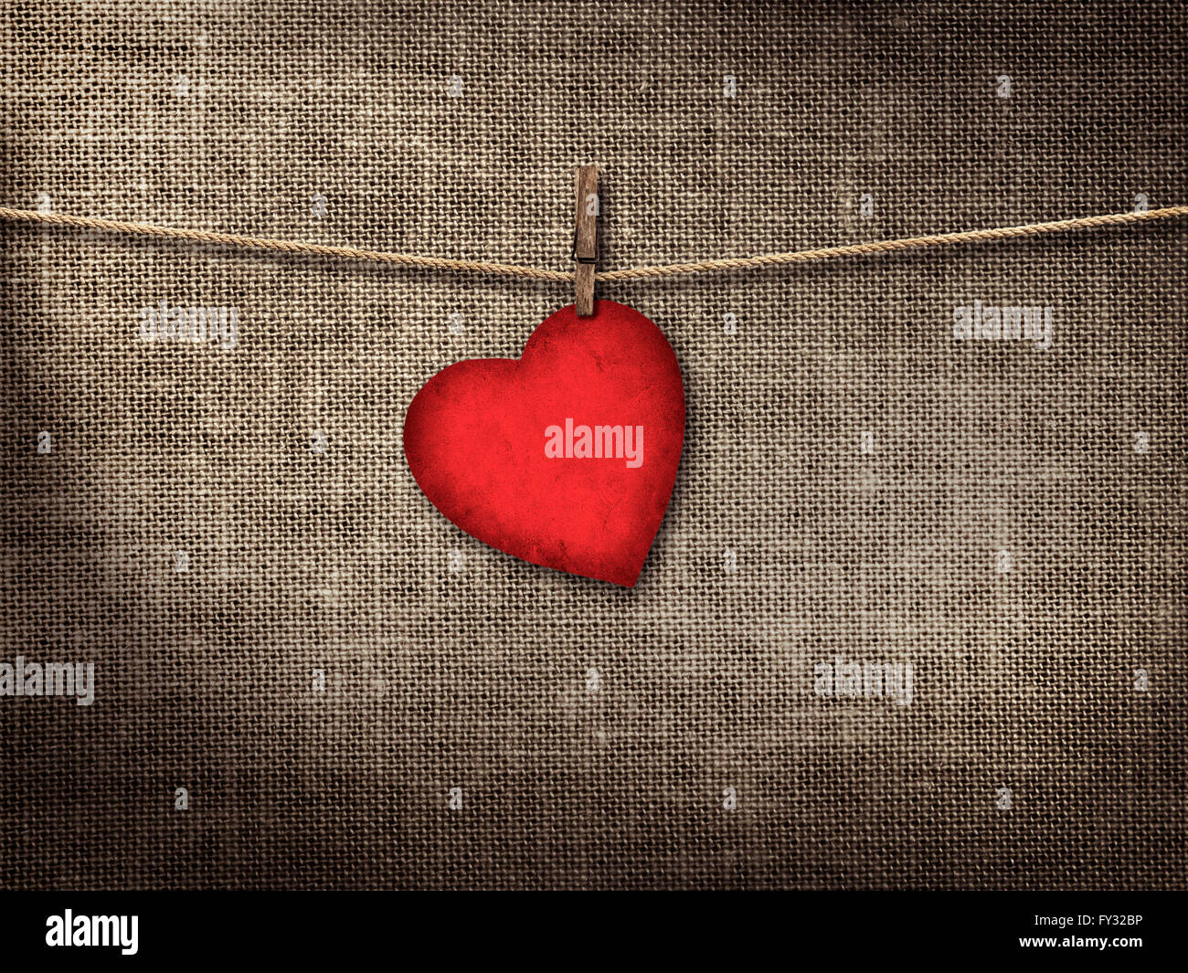 Valentine card heart shaped from old red paperr hanging on a clothesline on a linen background Stock Photo