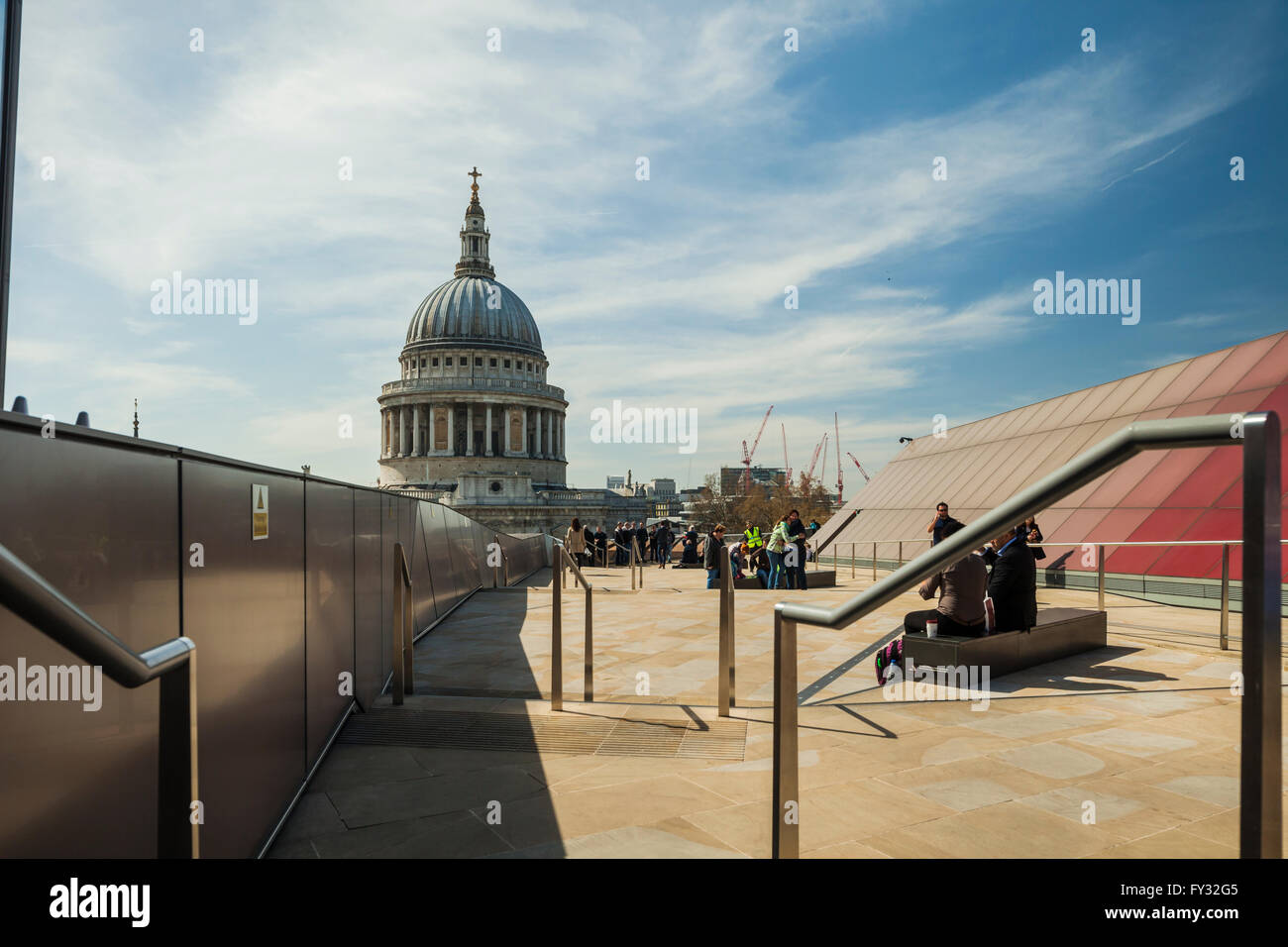 People enjoy sunny spring day on a roof top, St Paul's cathedral dome in the distance. London, England. Stock Photo
