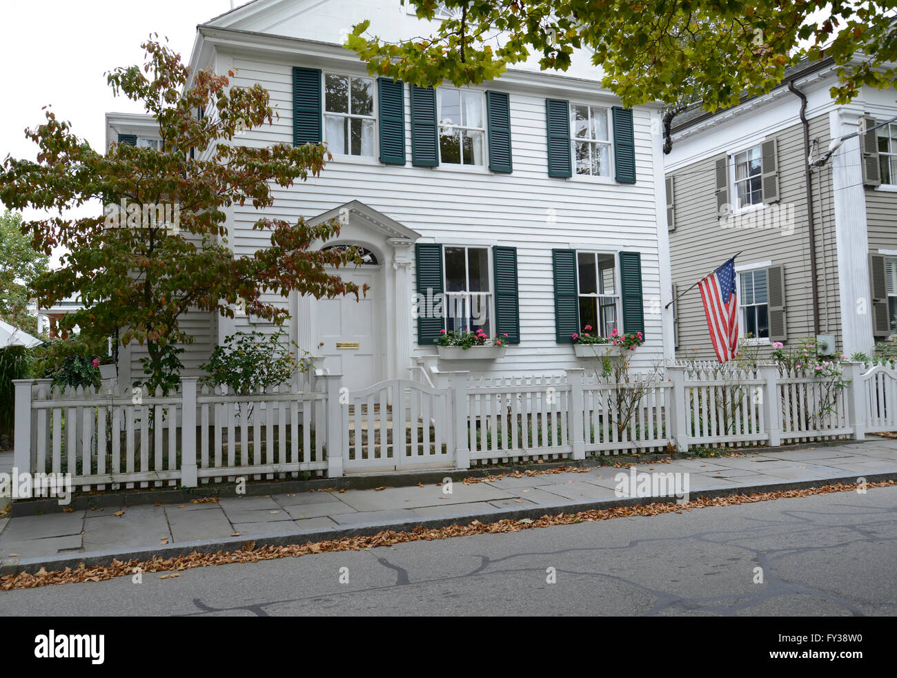 old federal style house in the quaint town of Stonington Connectict.  There is an American flag, white picket fence and slate si Stock Photo