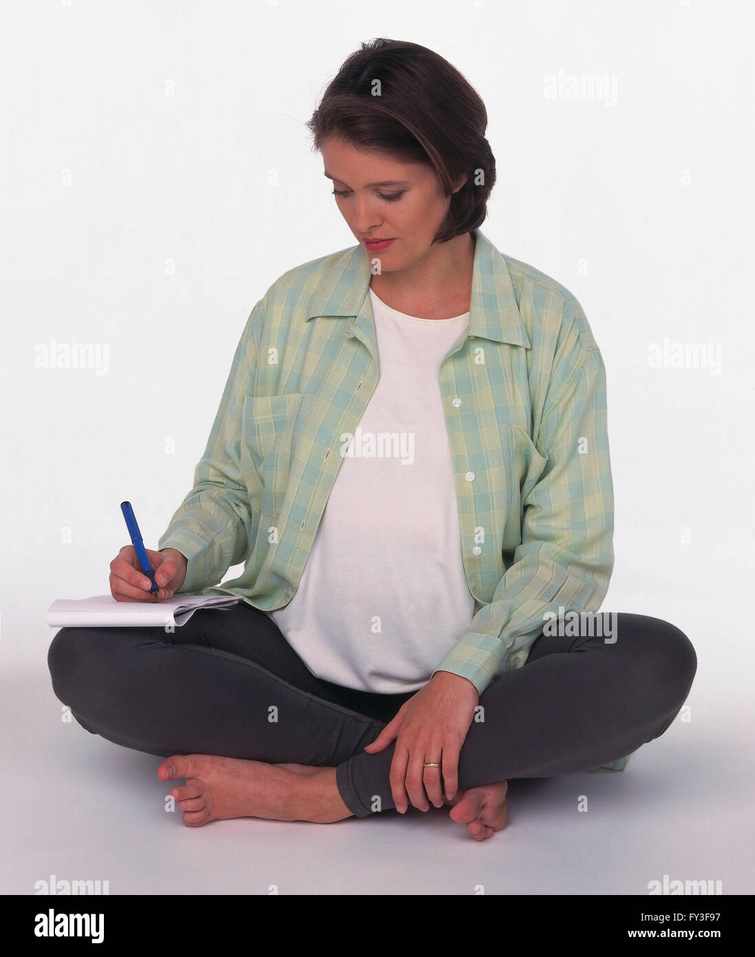 Pregnant Woman sitting crosslegged taking notes Stock Photo Alamy