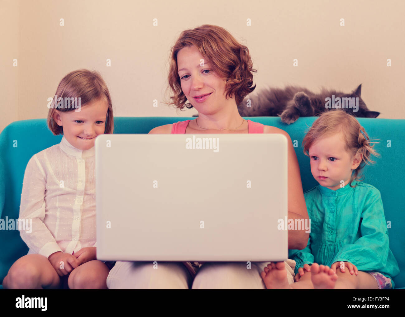 Mother with little daughters watching the laptop. Selective focus. Stock Photo