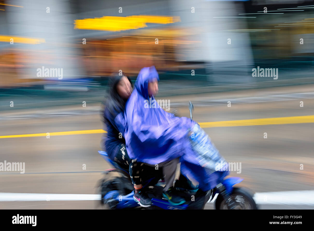 Shanghai, China - October 5, 2015: Couple riding an electric bike in the rain in Shanghai China. Stock Photo