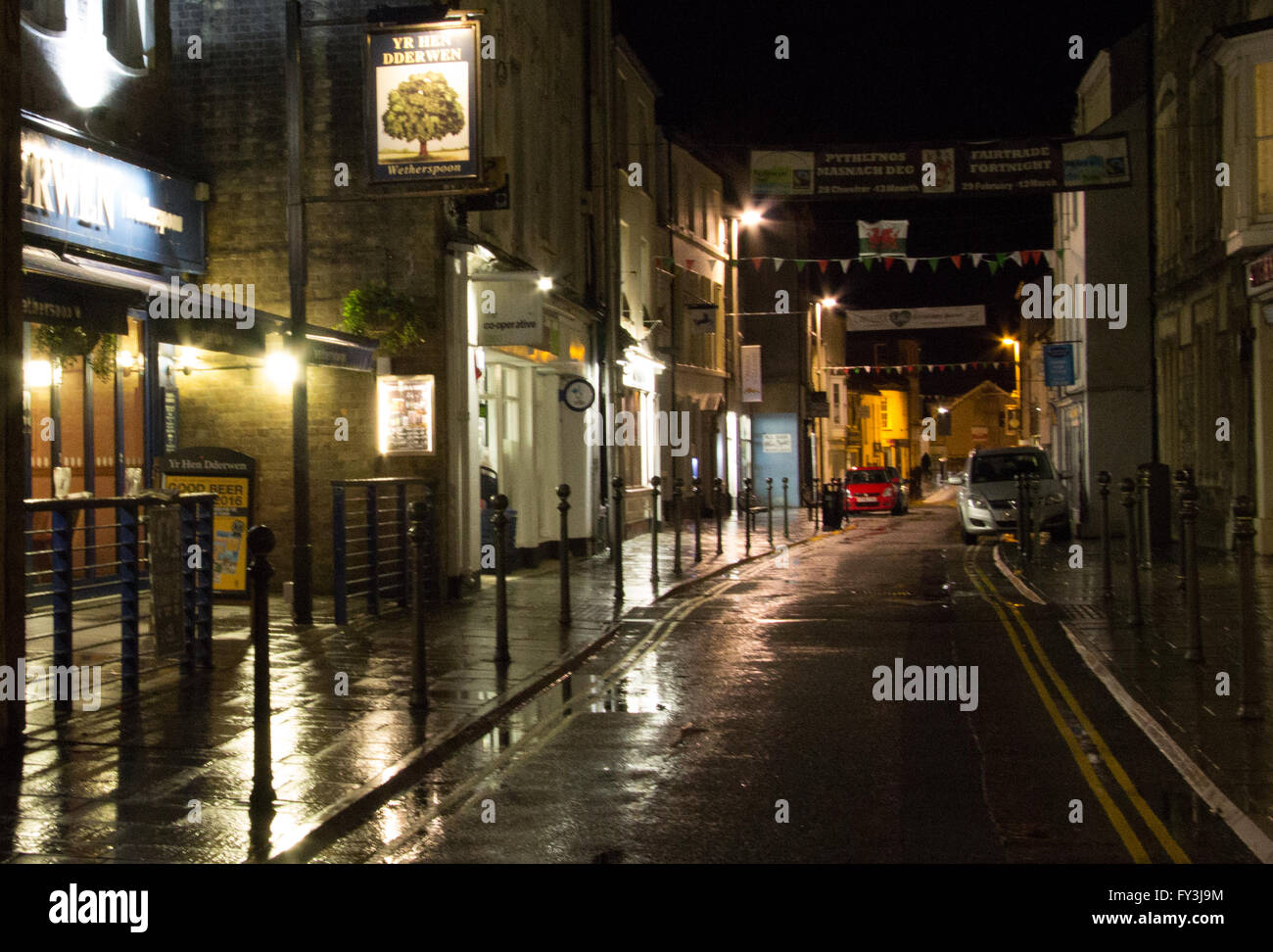 King Street, Carmarthen on a cold wet evening.  The shoppers had gone home, the street was quiet, but the lights shone brightly. Stock Photo