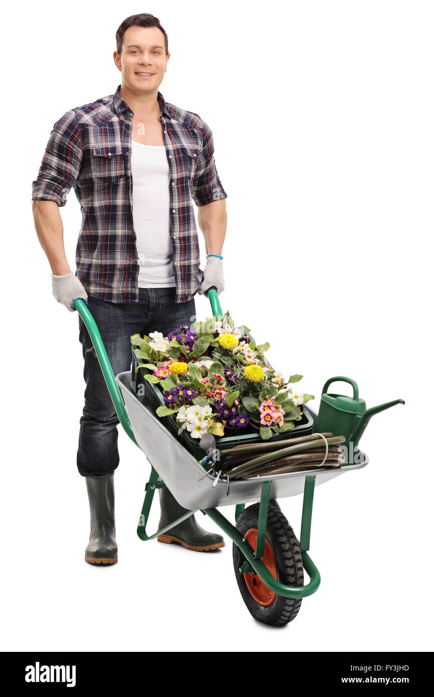 Full length portrait of a young guy posing with a wheelbarrow full of gardening equipment isolated on white background Stock Photo