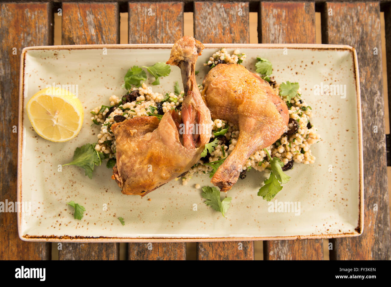 Confit chicken with lemon, olive and herb cous cous Stock Photo