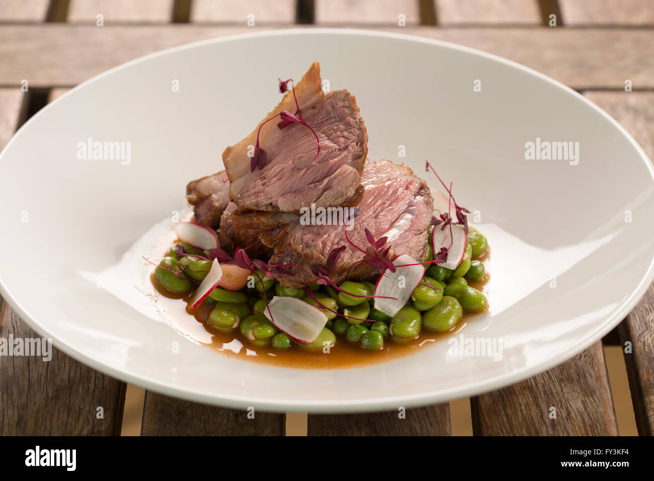 Roast rump of lamb, with broad beans, peas & radishes Stock Photo Alamy