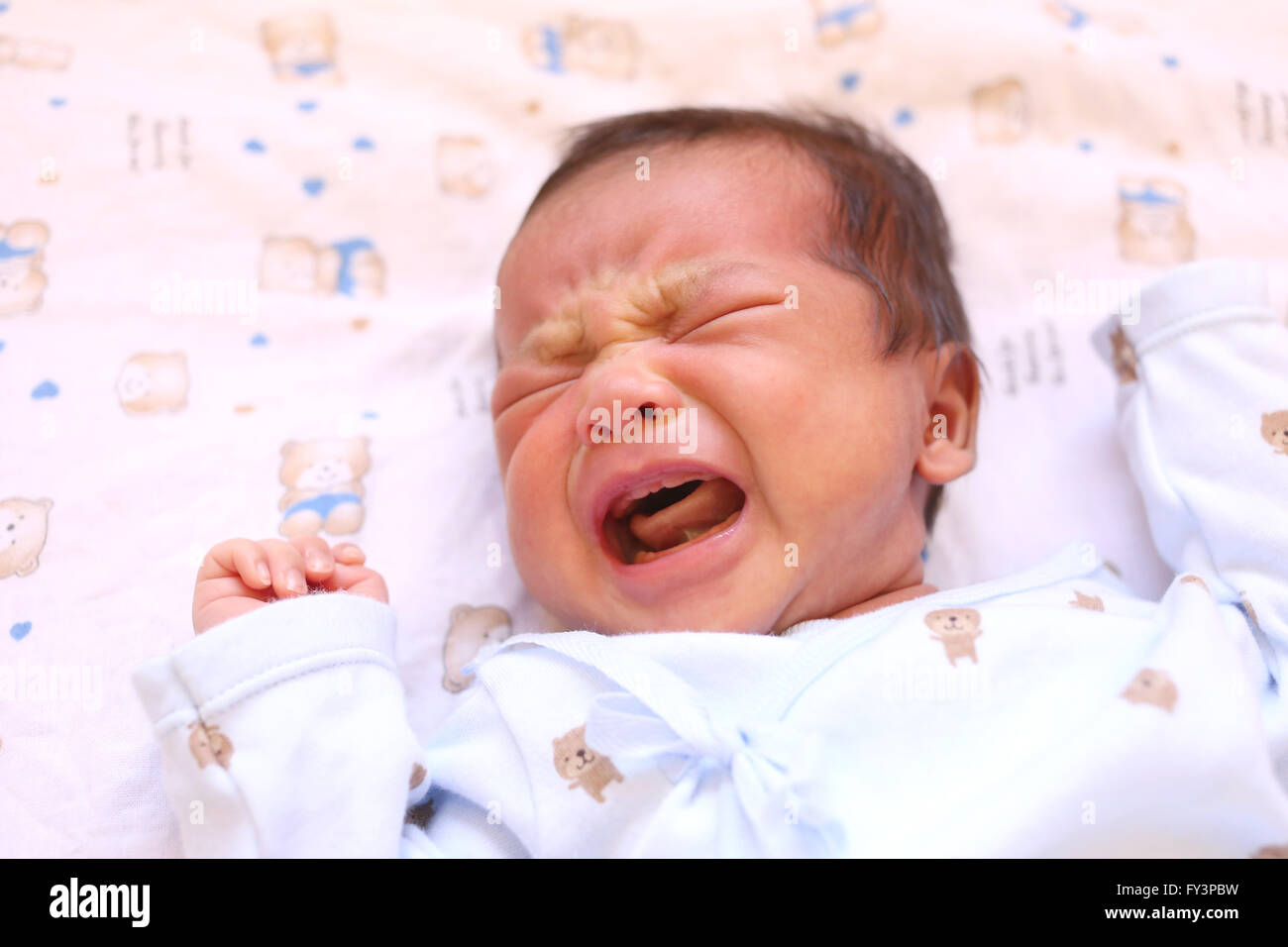 Newborn baby of asia crying on white bed and looked in a hungry milk. Stock Photo