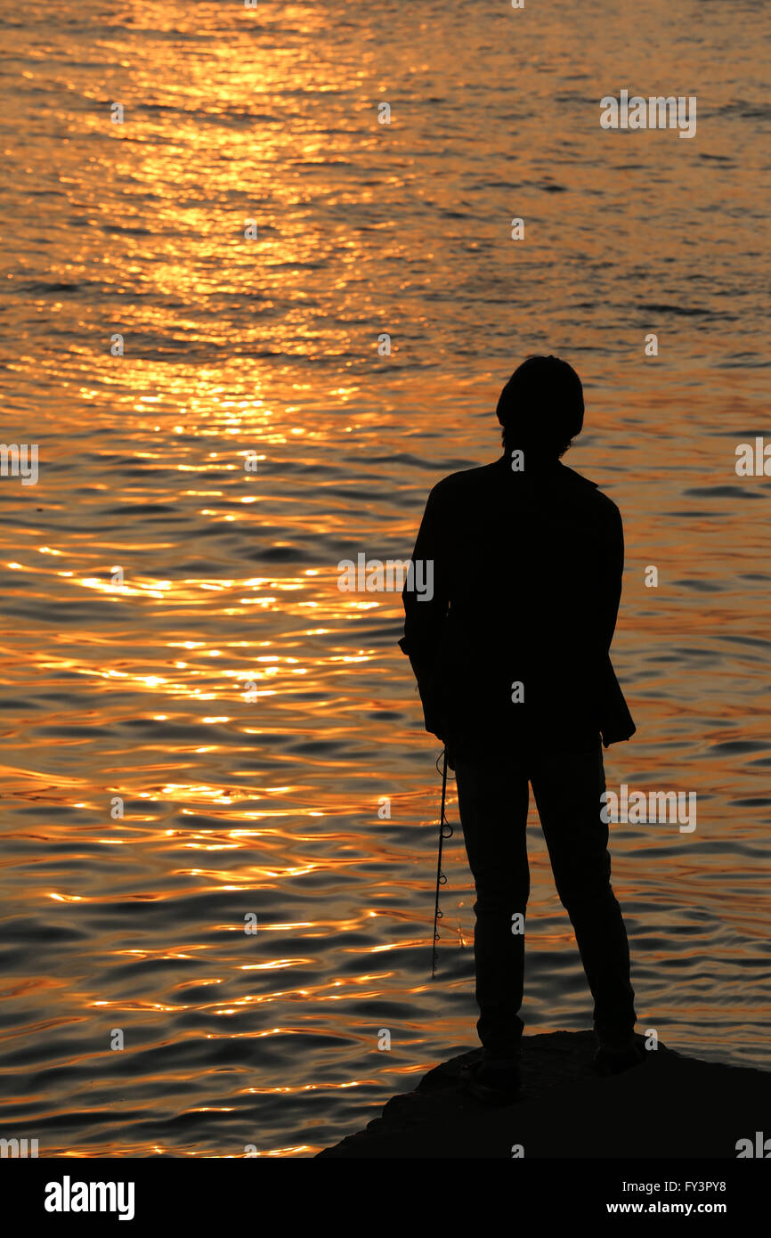 fisherman of silhouette style on seaside in the evening light sunset. Stock Photo