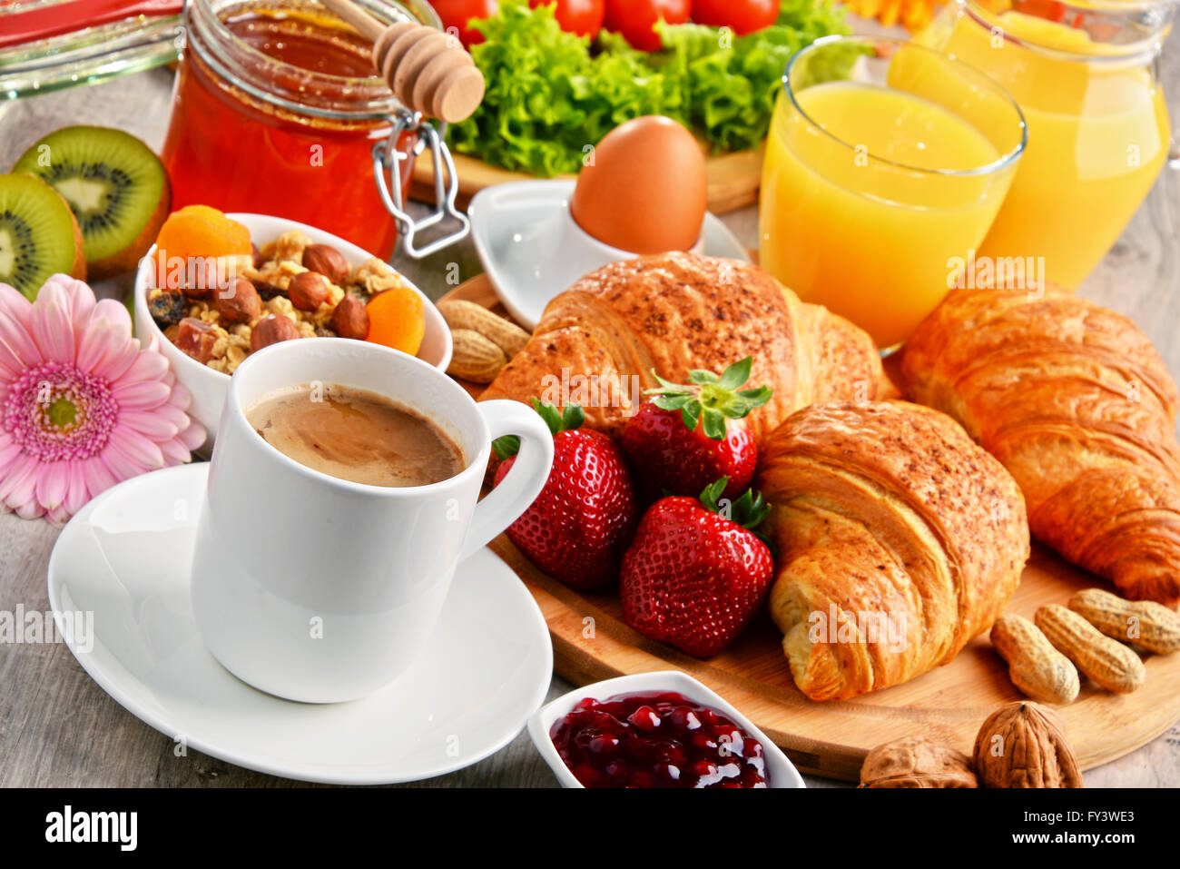 Breakfast consisting of croissants, coffee, fruits, orange juice