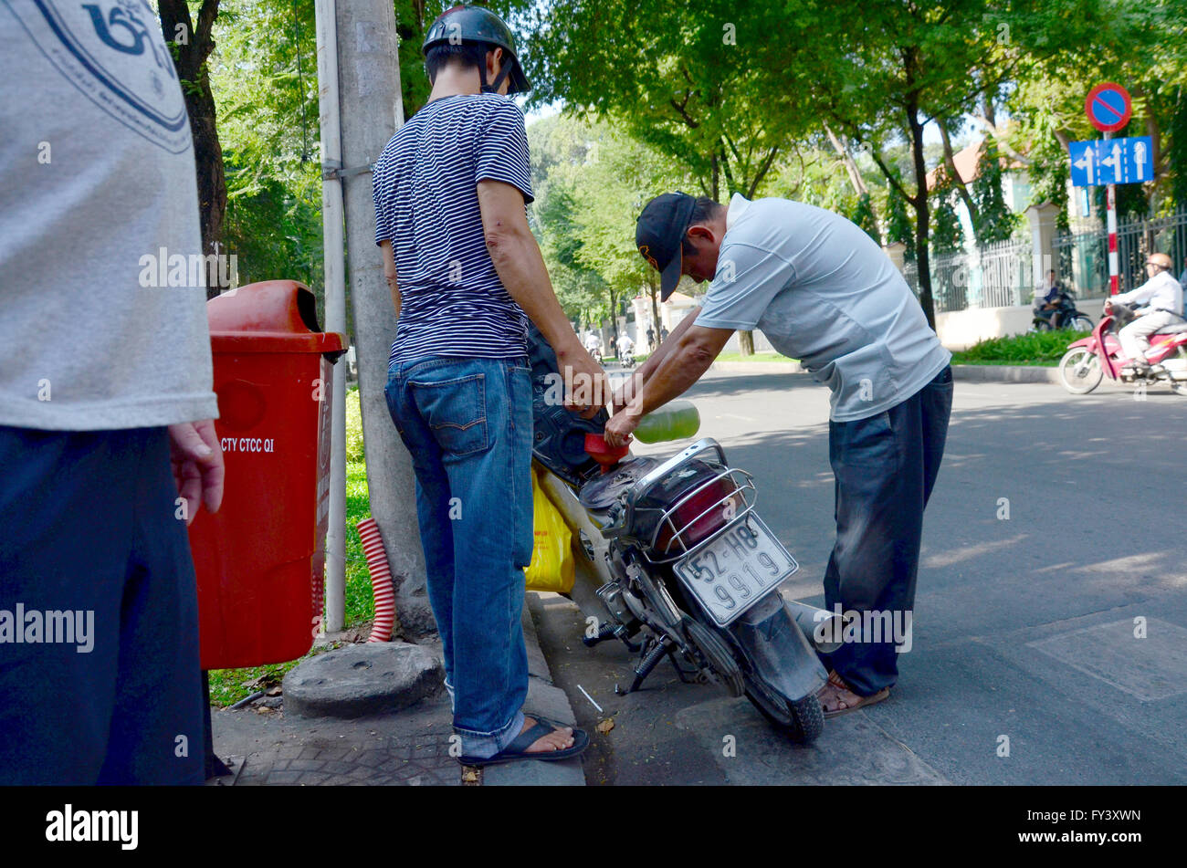 Vietnamese people fill the gas tank in motorcycle on the road at Saigon