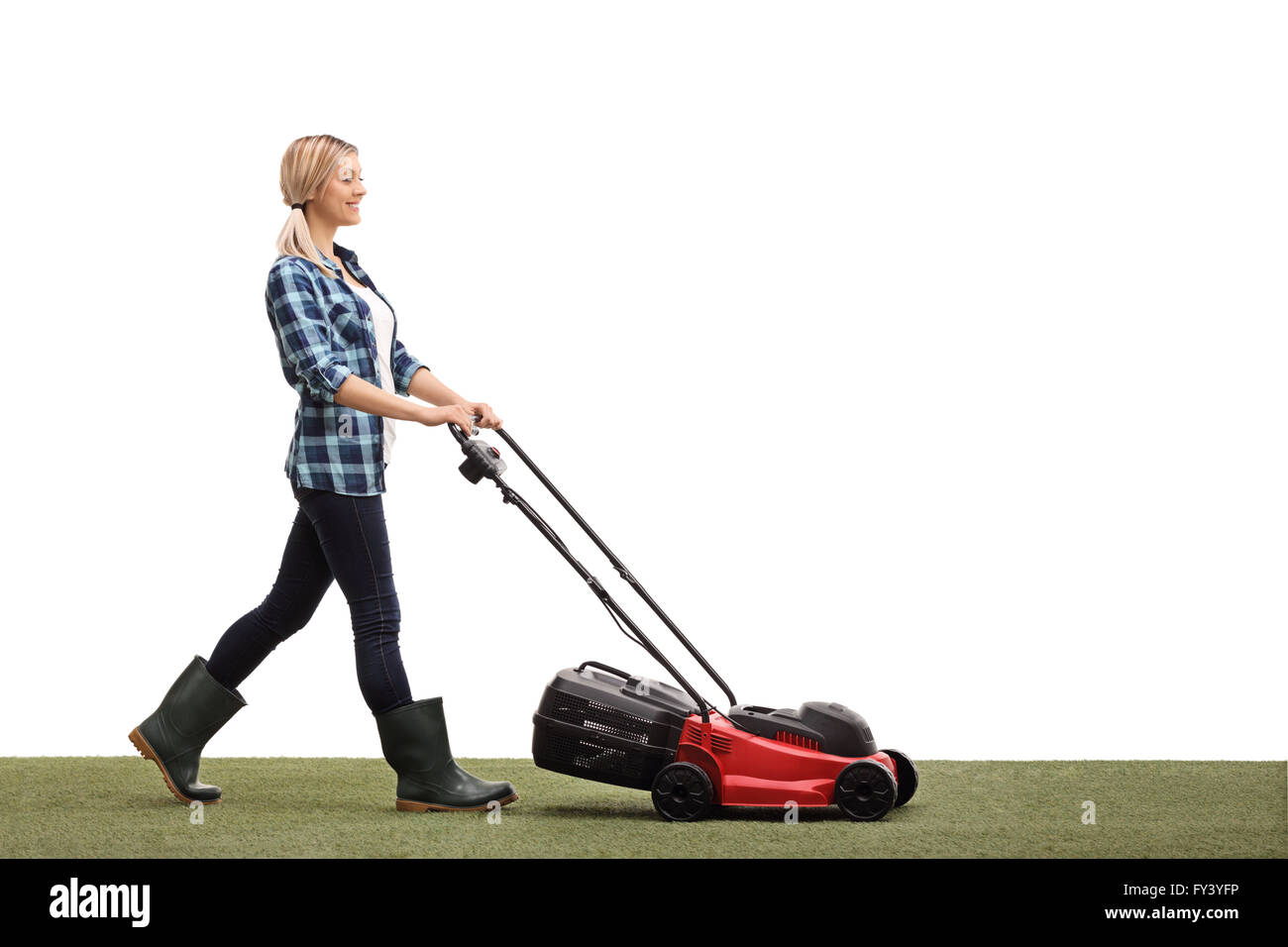 Profile shot of a young cheerful woman mowing a lawn with a lawnmower isolated on white background Stock Photo