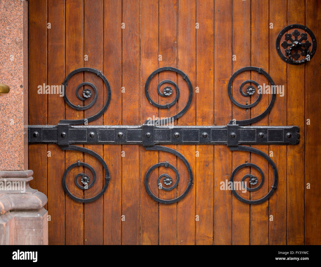 Ornate Door. A beautiful old huge wooden door has ornate metal patterns on it that are used to hold the door together. Stock Photo