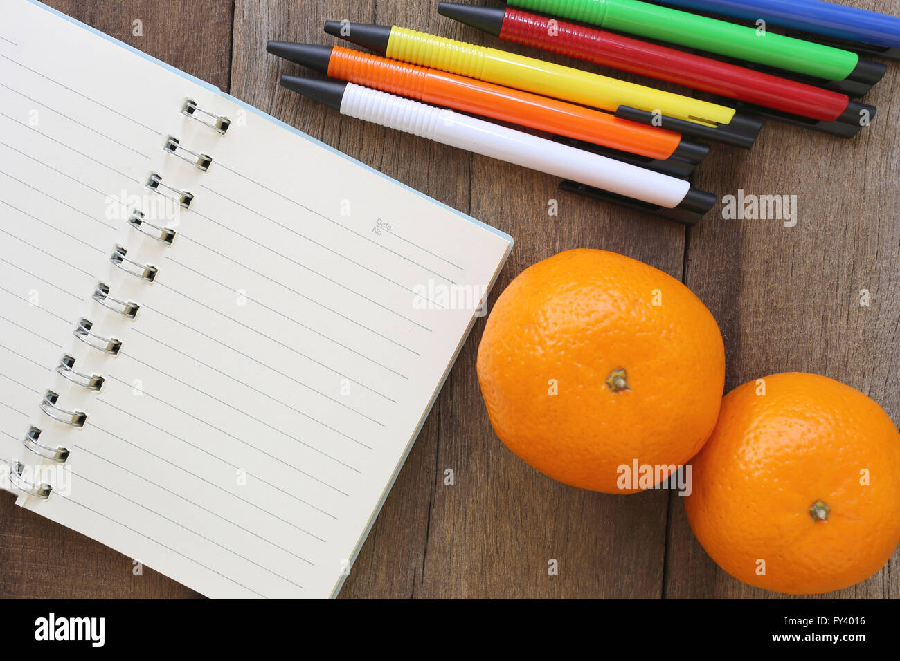 Notebook and mandarin oranges on old wood for the design background,Blank paper to take notes or add text to it. Stock Photo