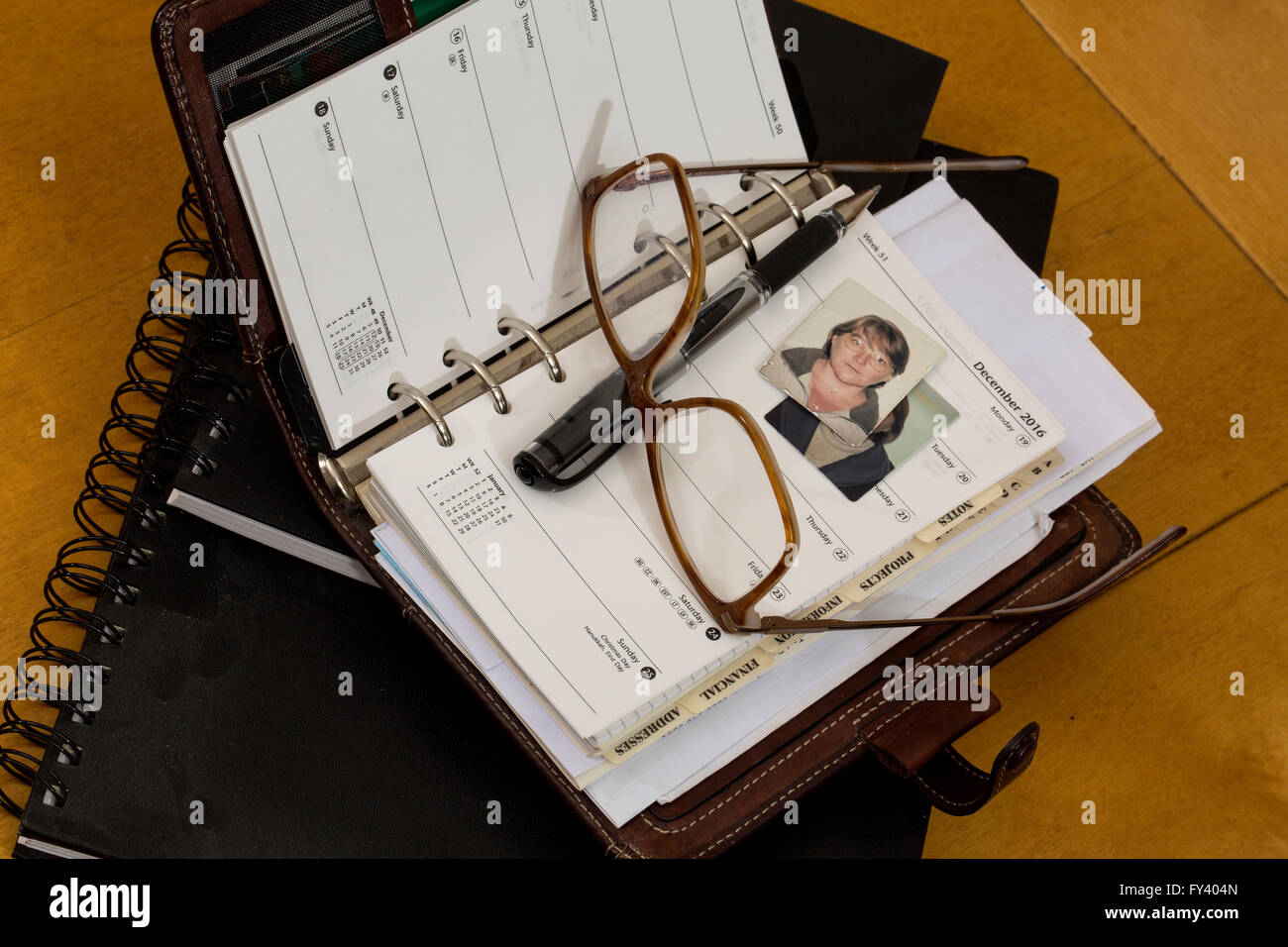 Plans for the Future. A diary open to December 25, glasses and a passport photo make a still life that is about planning ahead. Stock Photo