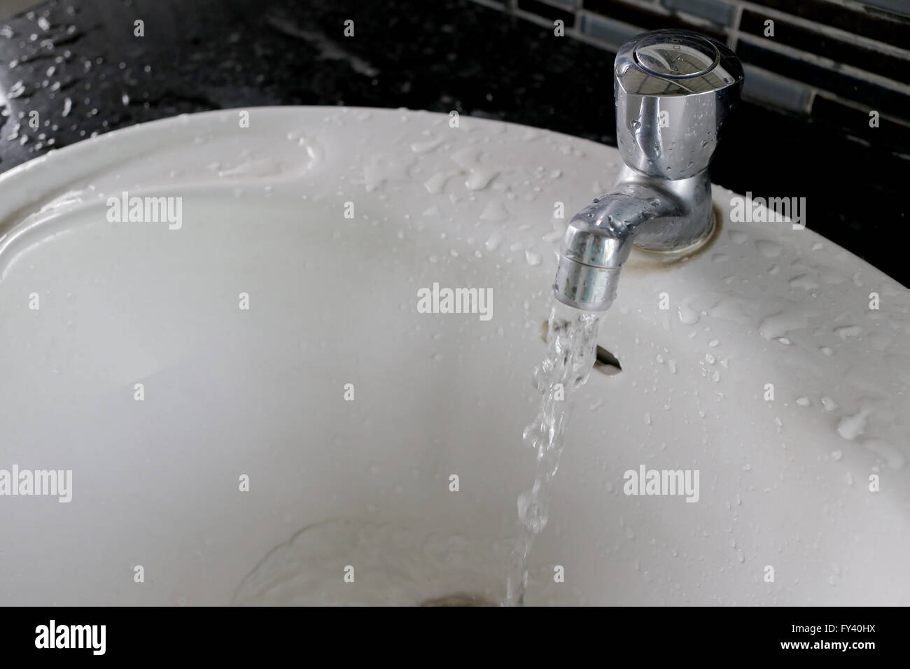 faucet with water flowing in the wash basin. Stock Photo