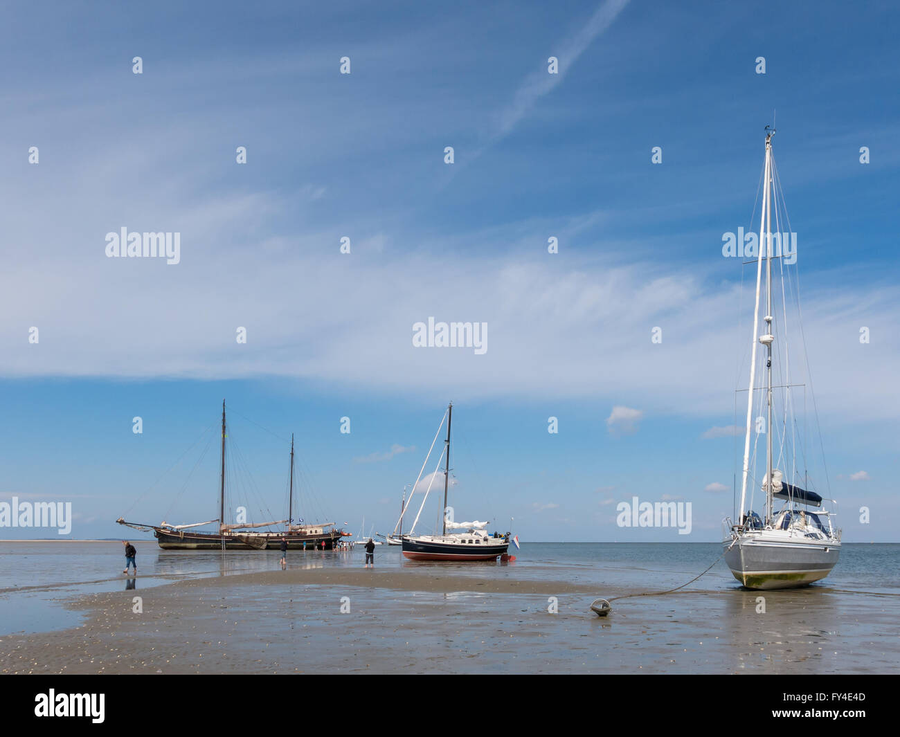 Sailboats drying out at low tide on the wetlands of the Waddensea in the Netherlands Stock Photo