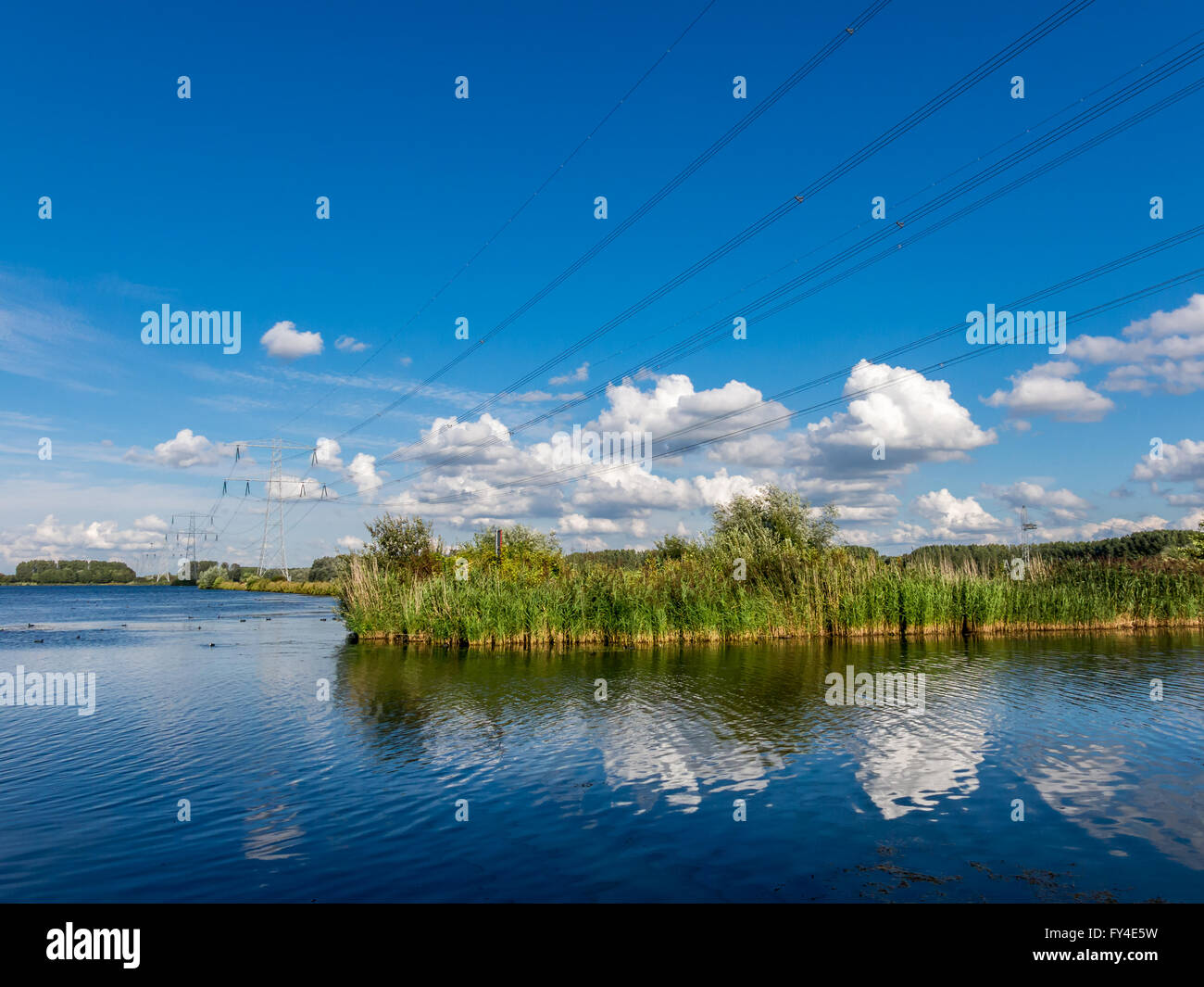 Lake landscape with high voltage electric power wires, Flevoland, Netherlands Stock Photo