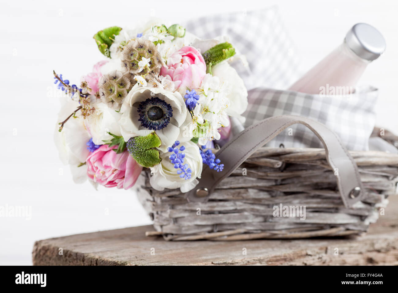 Bouquet from pink tulips, violet grape hyacinths, white anemones, violet veronica and white buttercup in picnic basket Stock Photo