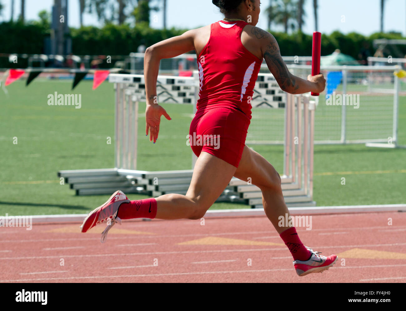 Female track athlete running the anchor of a 4x100 relay team Stock Photo