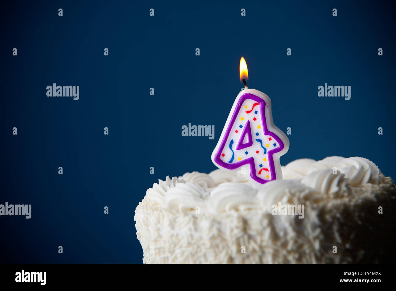 White iced cake on blue background with candles to celebrate various birthdays. Stock Photo