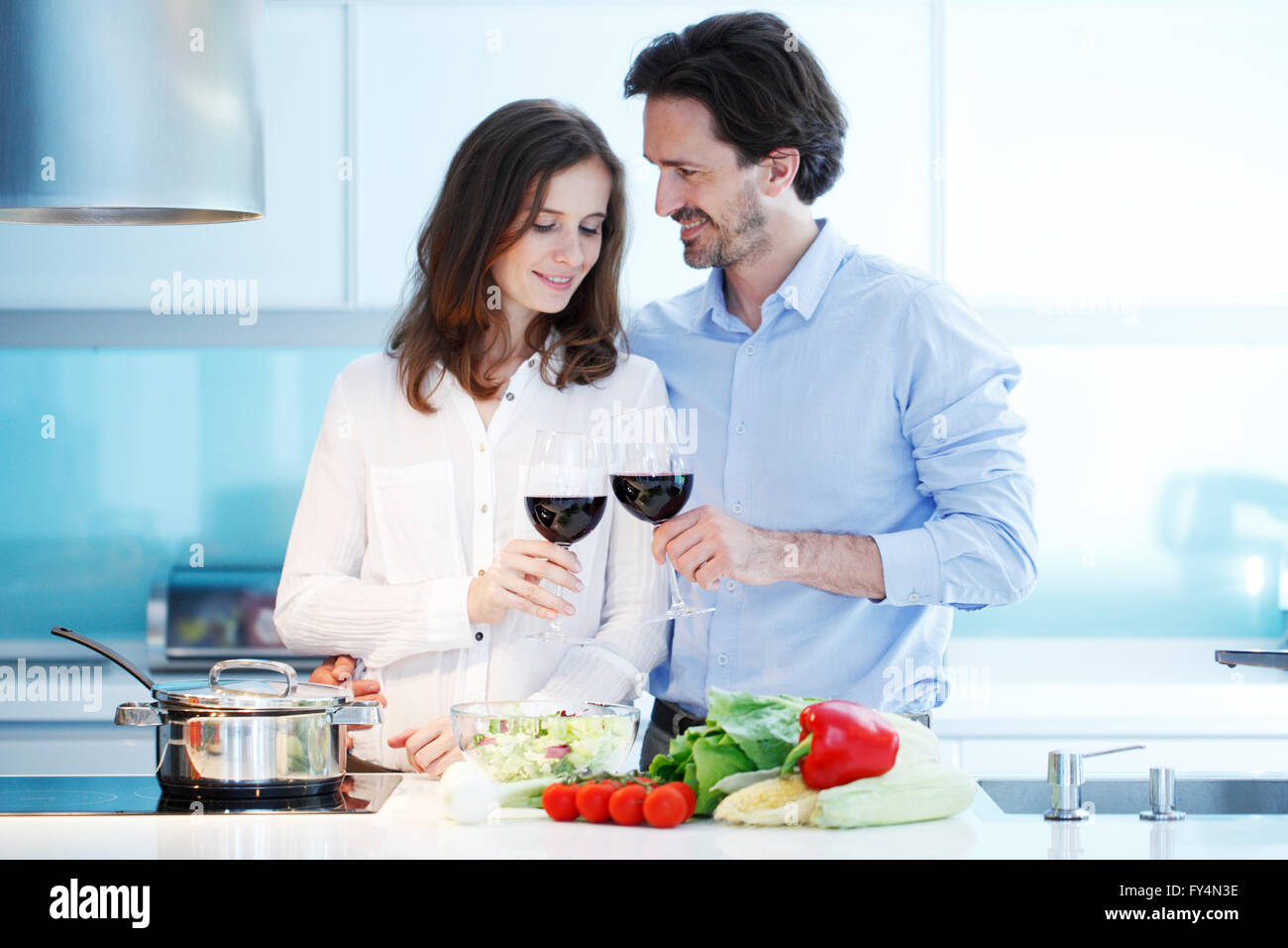 Portrait of a couple having a glass of red wine while cooking dinner Stock Photo