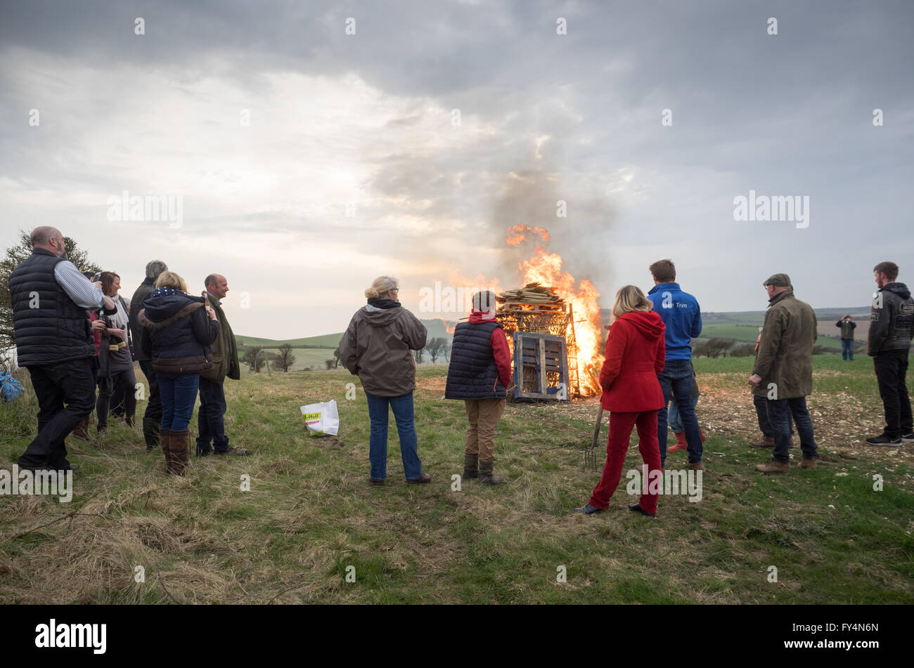 a group of spectators watching standing around a lit fire beacon for queen's 90th birthday in Whitwell, Isle of Wight, UK Stock Photo
