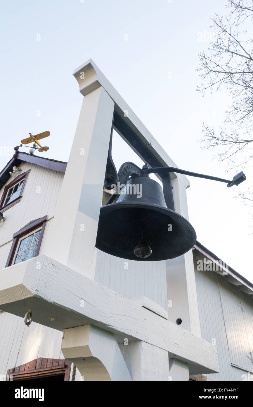 Old Fashion Hanging Clapper School Bell in Front of Barn, USA Stock Photo