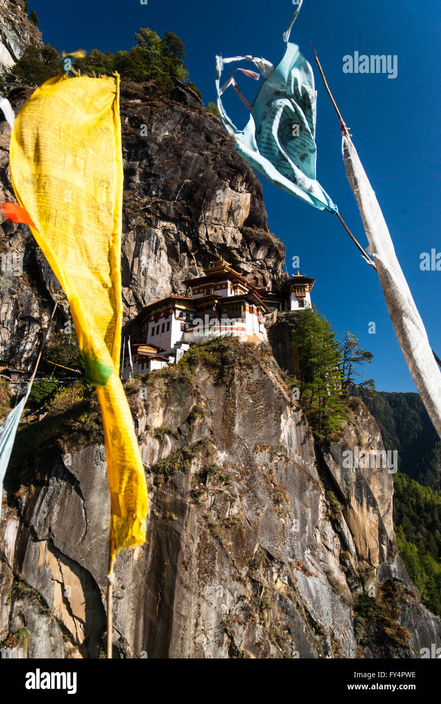 View through prayer flags to Tiger's Nest (Taktshang) Monastery, perched on cliff near Paro, Bhutan Stock Photo